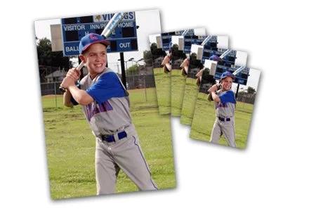 Young boy in baseball uniform holding a bat, ready to swing, on a baseball field.