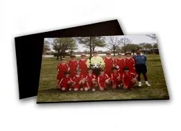 Group of children in red sports uniforms posing outdoors with a coach or adult.