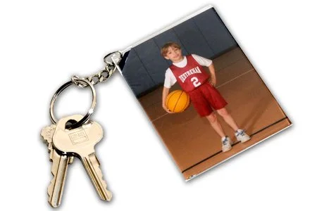 A keychain with a picture of a young boy in a red basketball uniform holding a basketball.