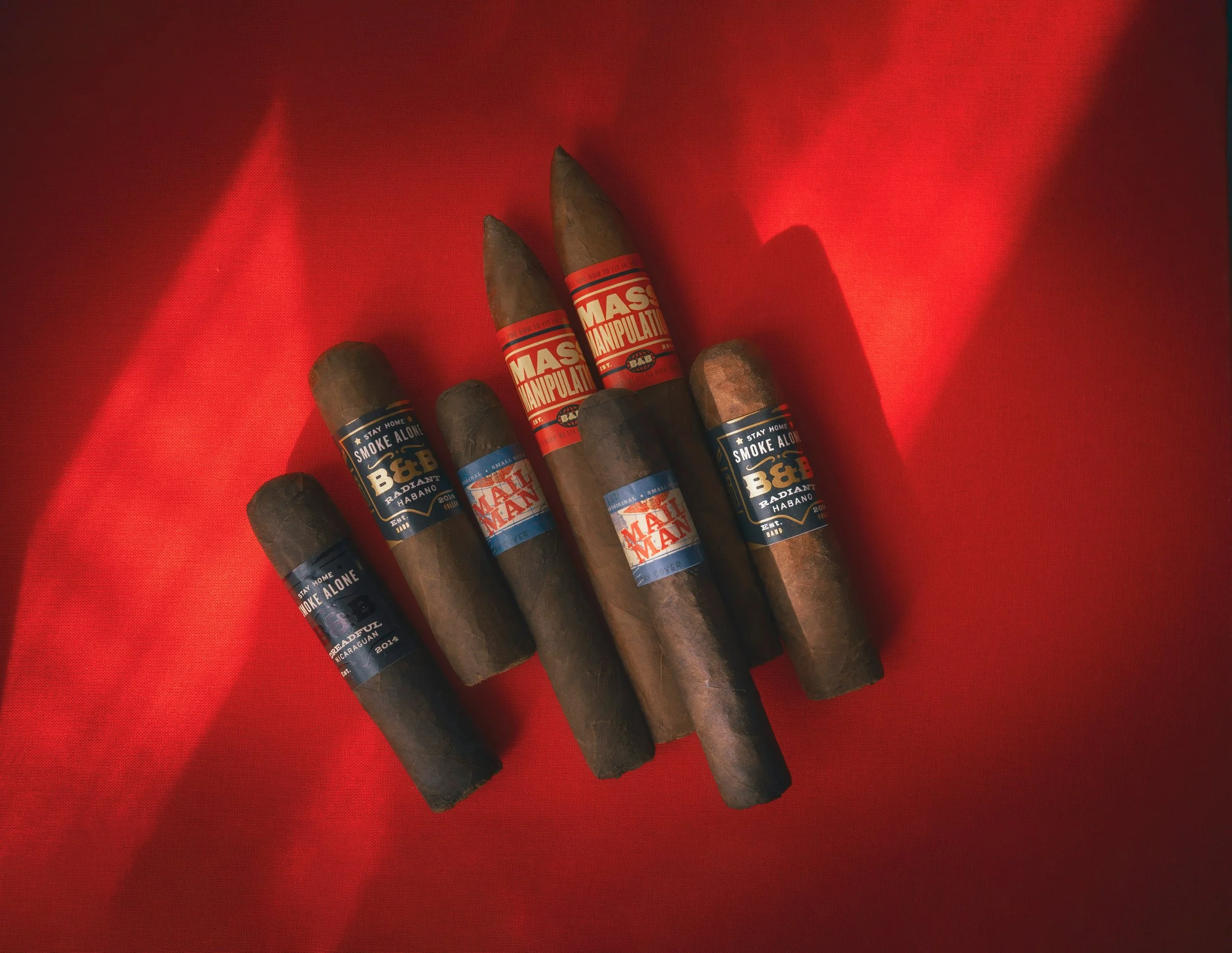 Five cigars with colorful bands, resting on red fabric.