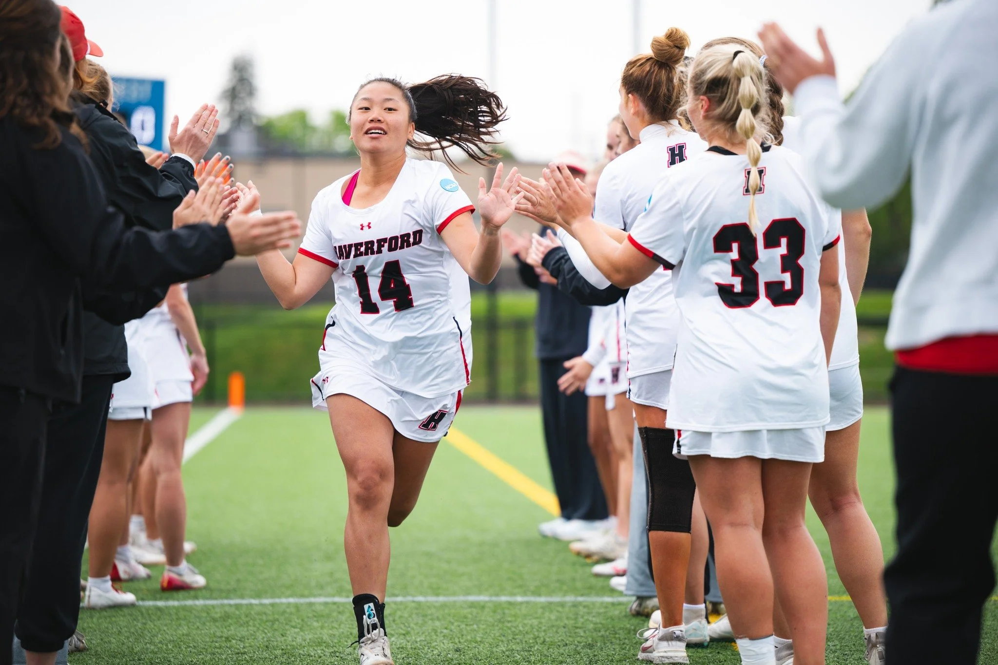 A Haverford women's lacrosee player runs through a tunnel of her teammate exchanging high fives.