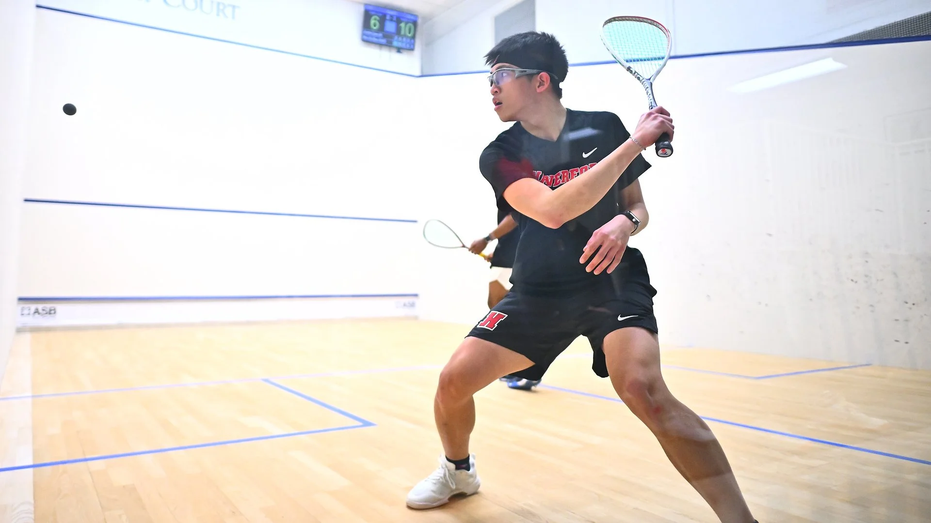 A Haverford squash player prepares to return the ball during a match on an indoor court.