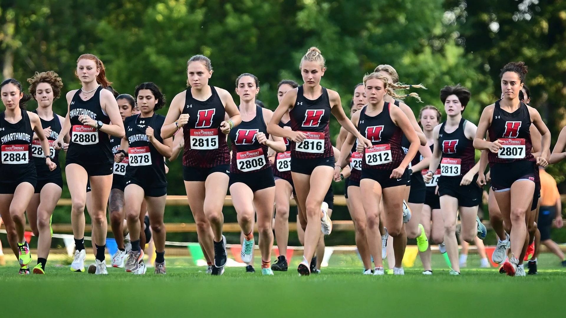 Group of Haverford Women's Cross Country athletes participating in a race through Haverford's Cross Country course, wearing Haverford singlets and numbered bibs.