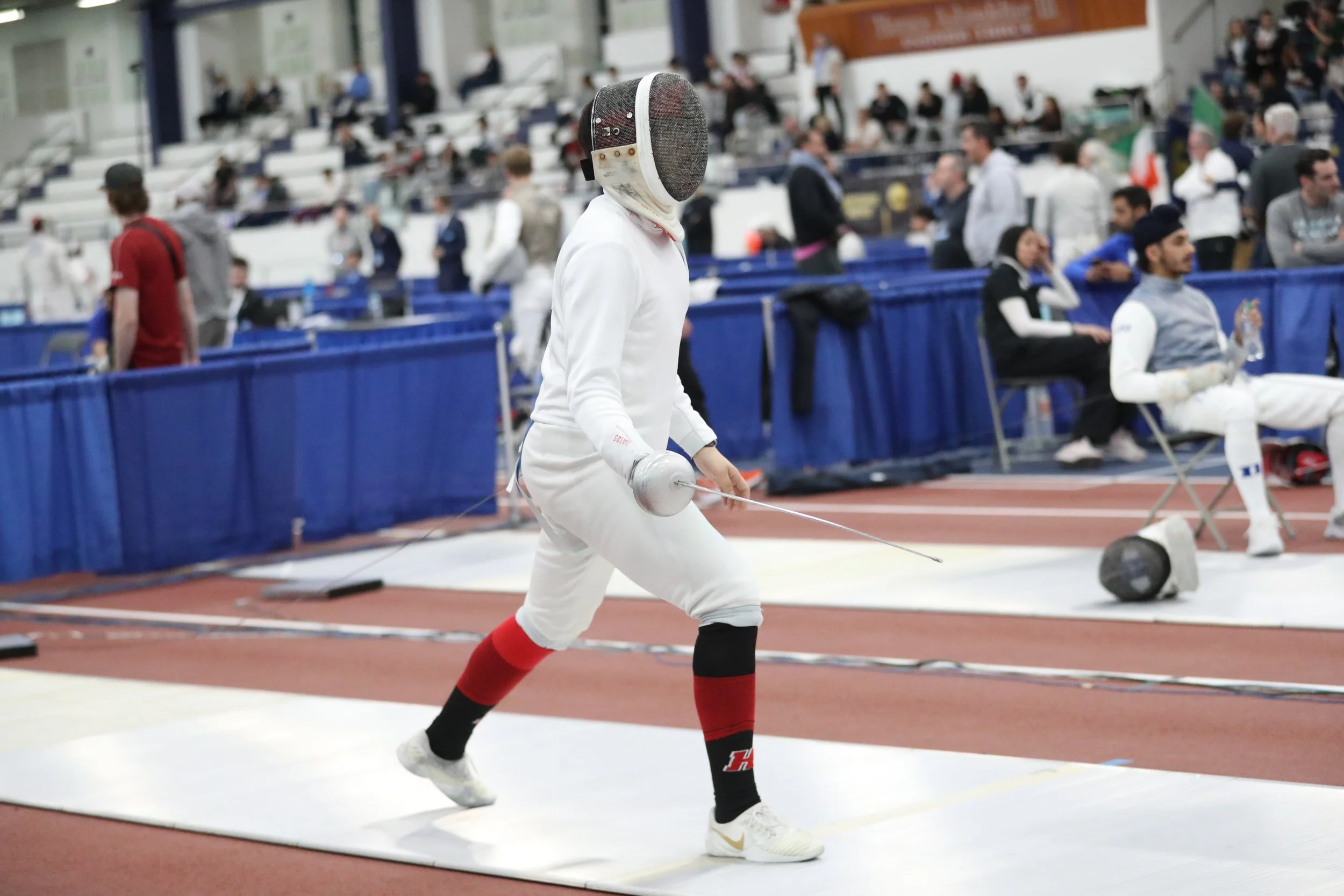 A Haverford fencing player in full protective gear lunges during a match.