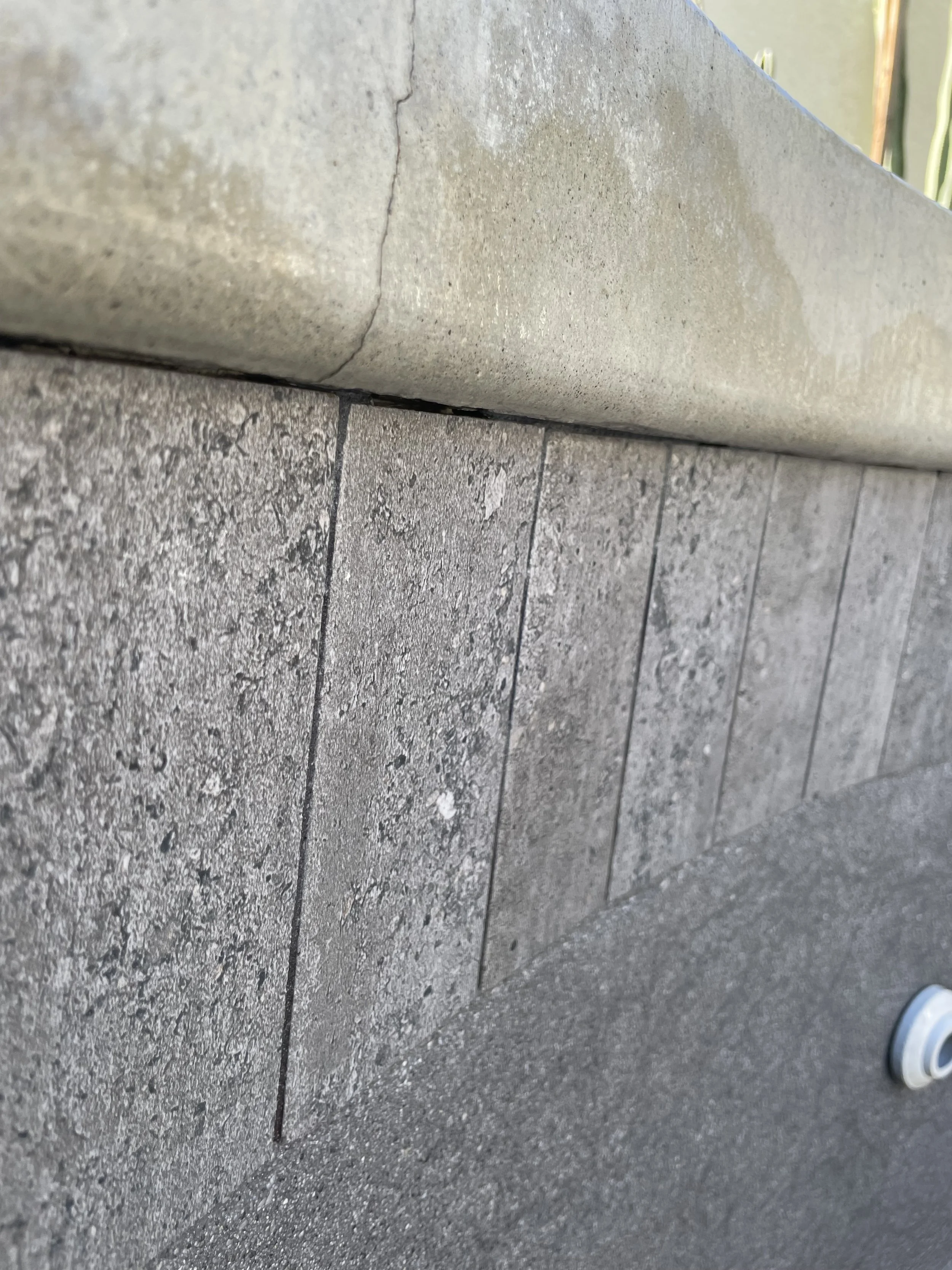 Close-up of a brick wall with a concrete ledge above it.