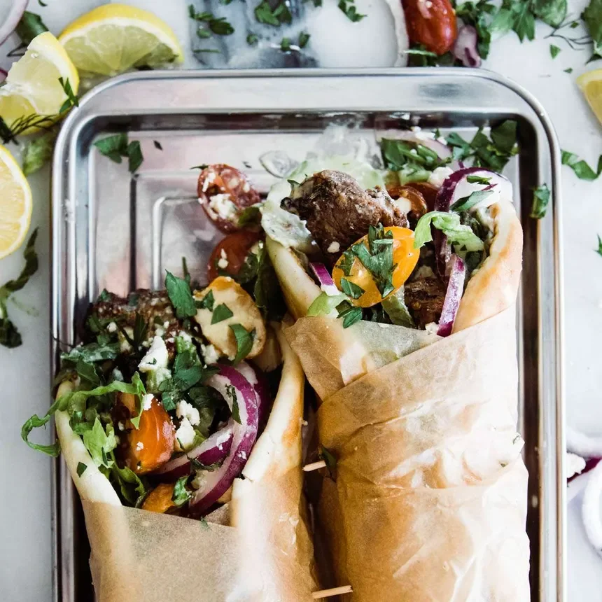 A plate of mixed vegetable curry with white rice on the side, served on a white dish on a wooden table.