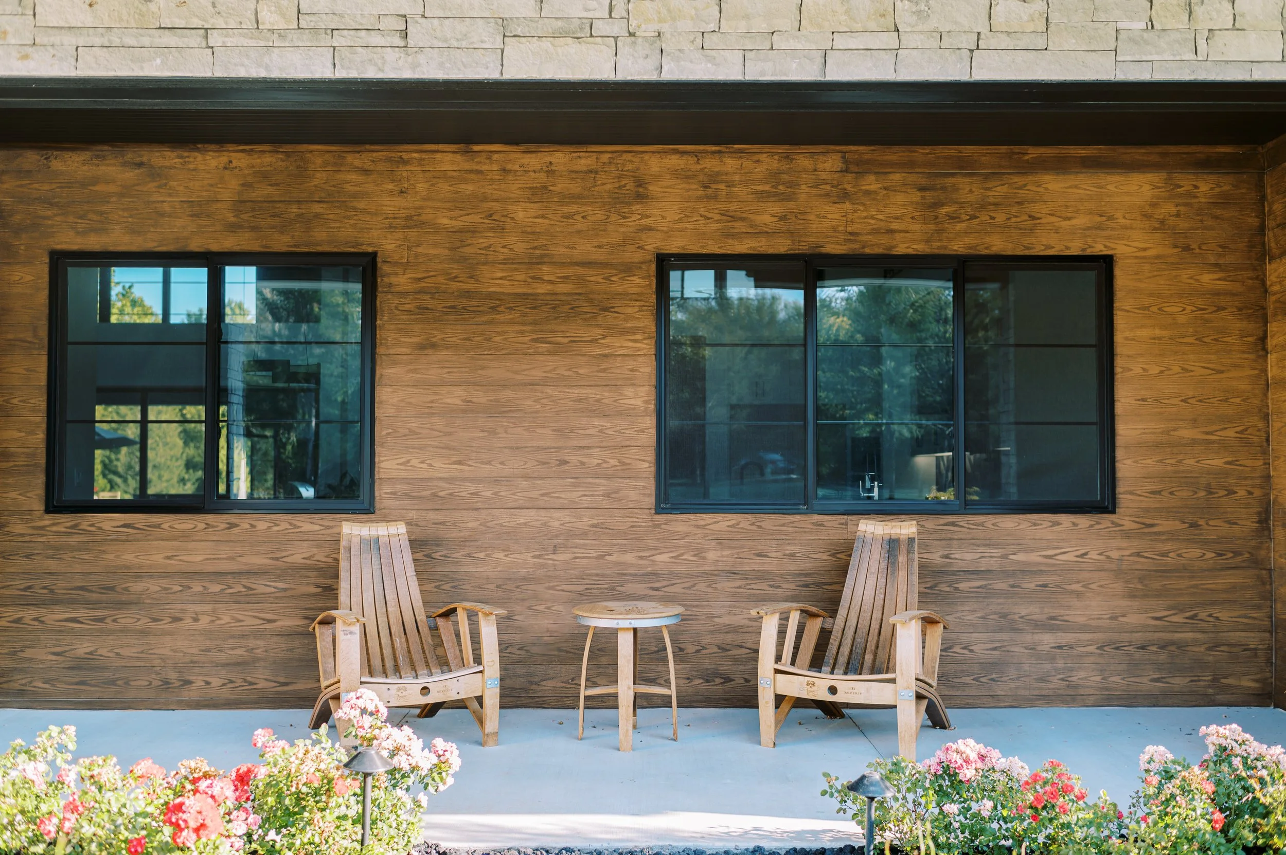 Custom mountain home exterior with wood siding, covered patio seating, and warm architectural detailing.