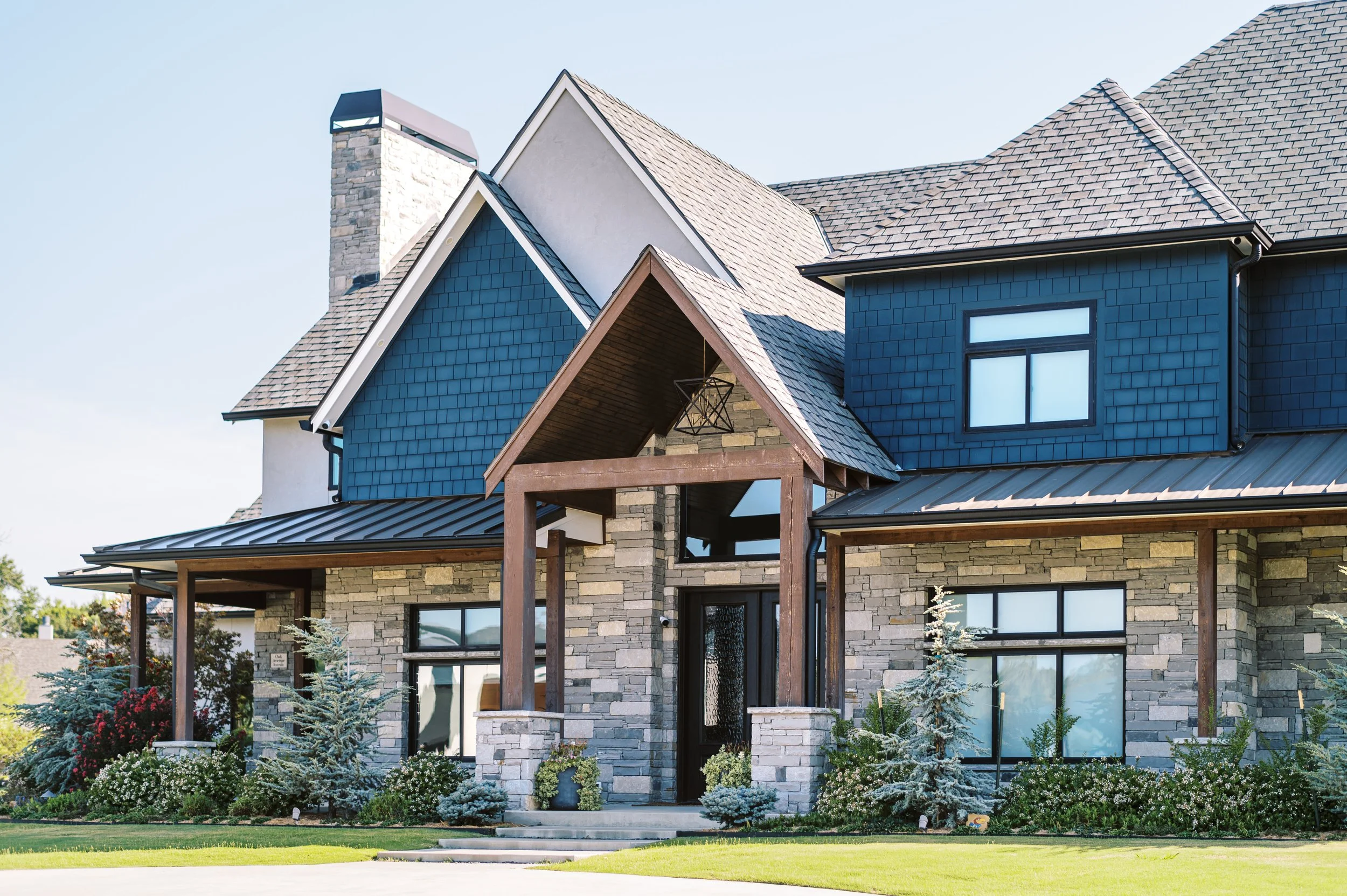 Luxury custom mountain home exterior by Snow Peak Customs featuring stone facade, timber entry, and mountain modern architecture.