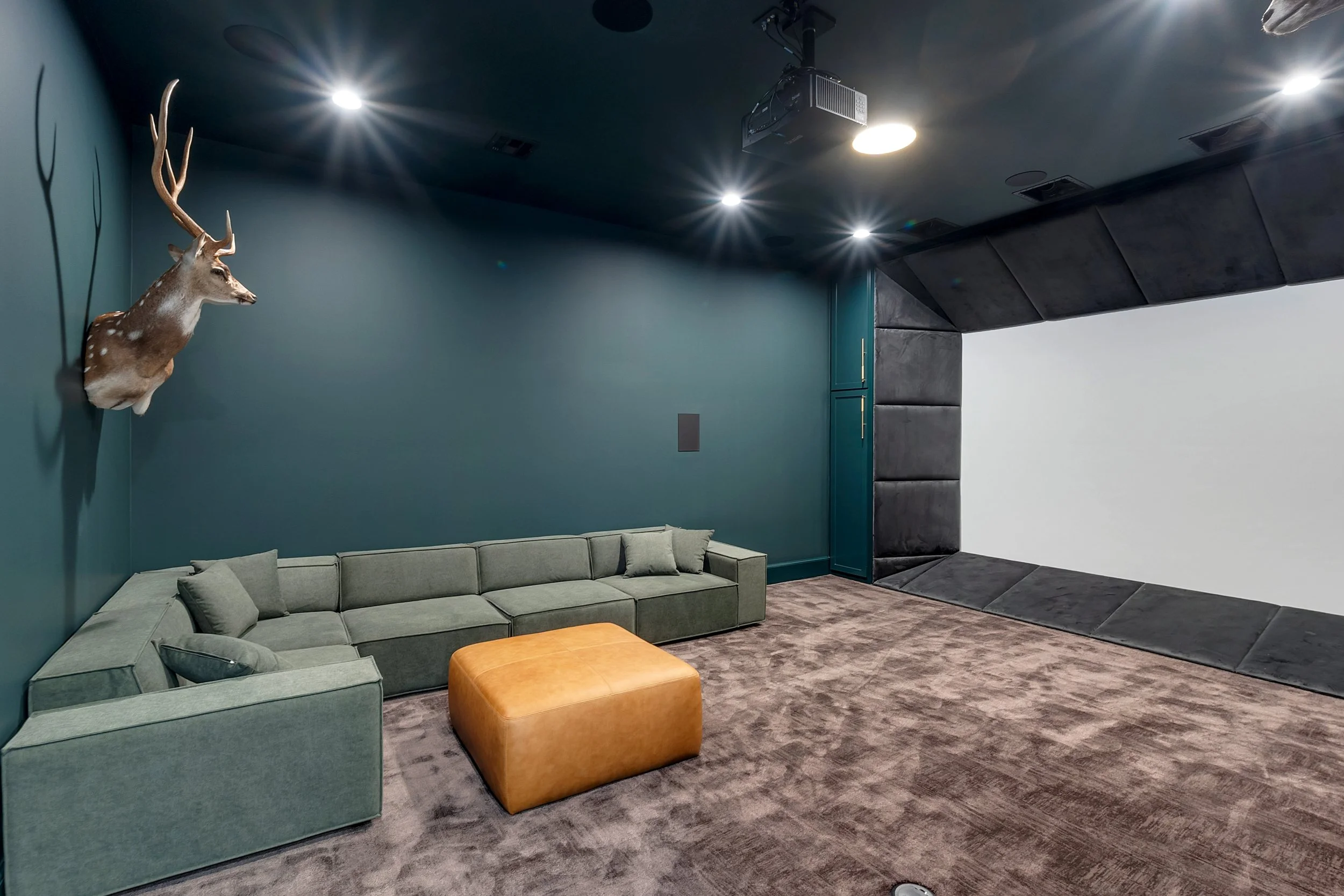 Luxury custom home theater featuring tiered seating, acoustic wall panels, and a large projection screen.