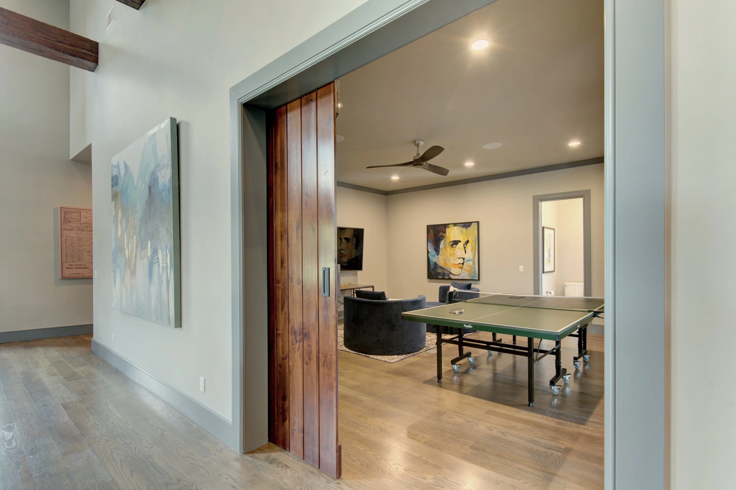 Luxury custom game room featuring a sliding wood door, ping-pong table, and refined modern finishes.