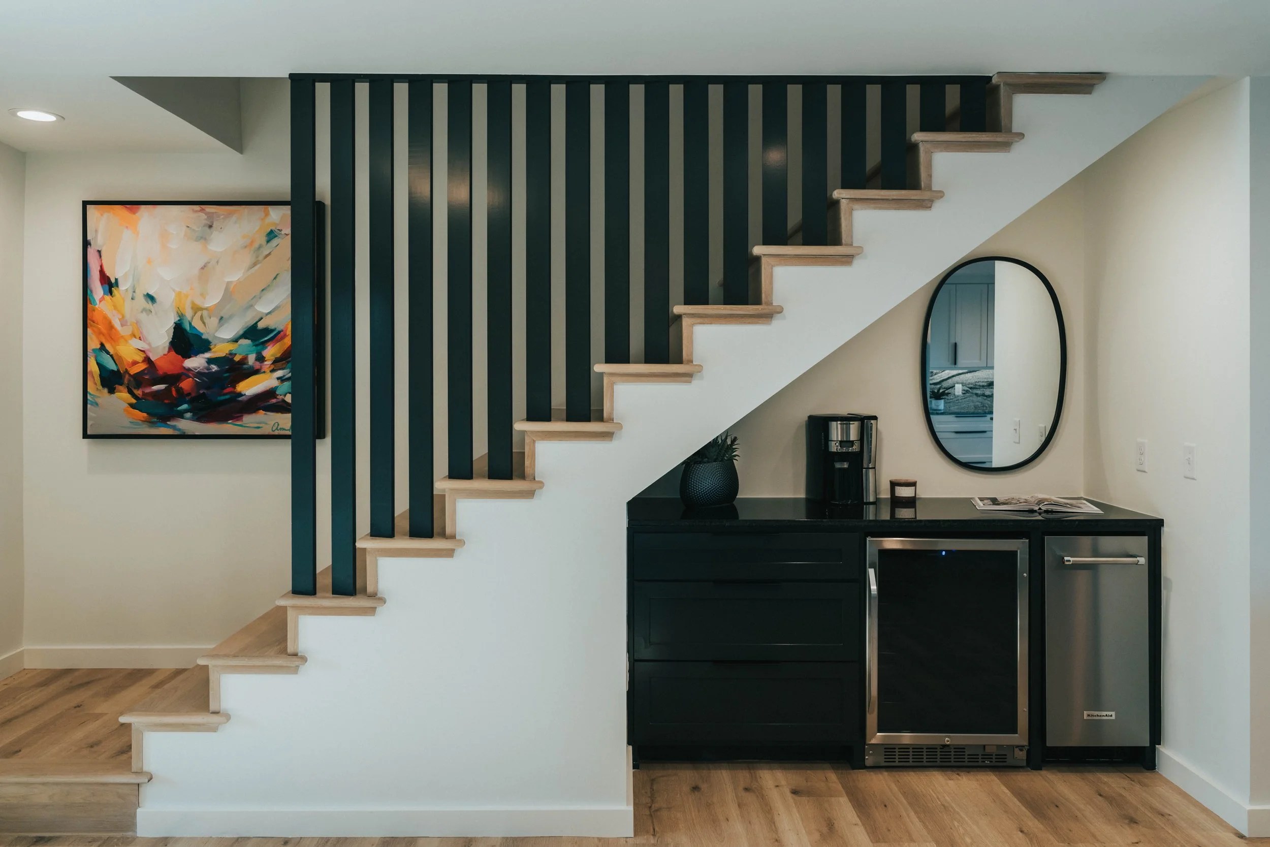 Mountain-modern remodel by Snow Peak Customs featuring a custom staircase with wood treads, vertical slat detailing, and an integrated lower-level kitchenette, designed for refined everyday living.