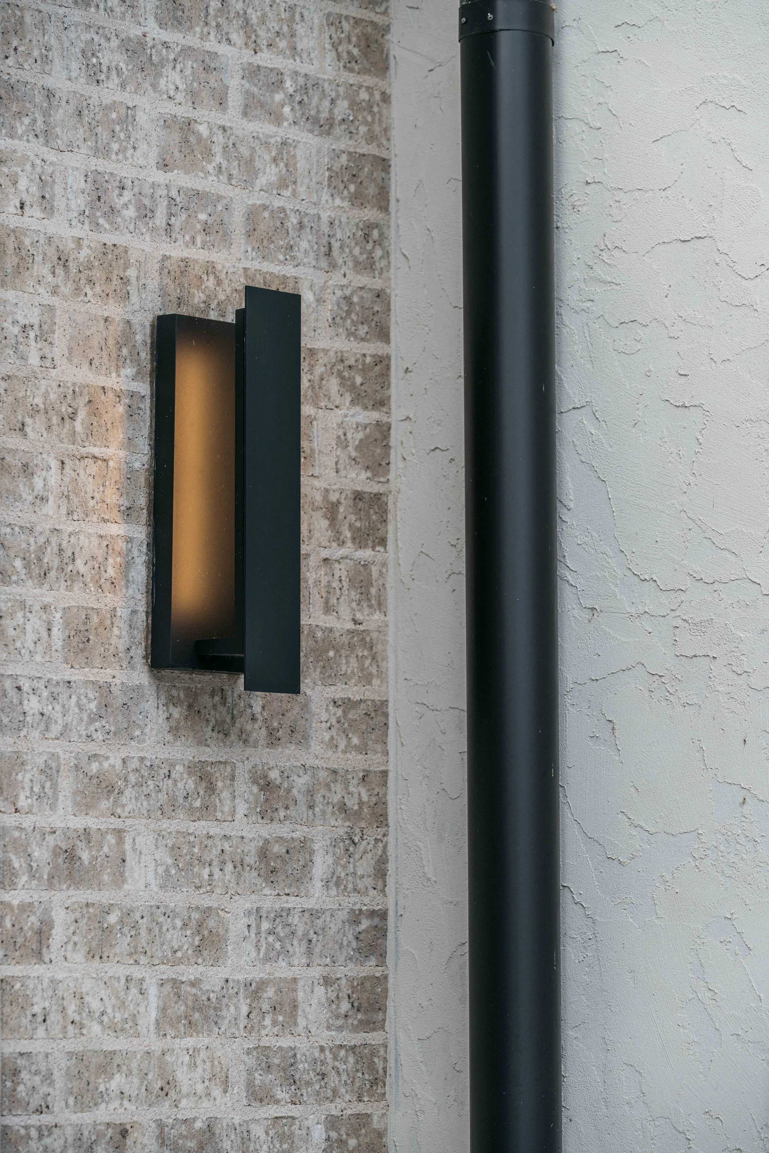 Modern architectural wall sconce mounted on textured stone, highlighting custom lighting design.