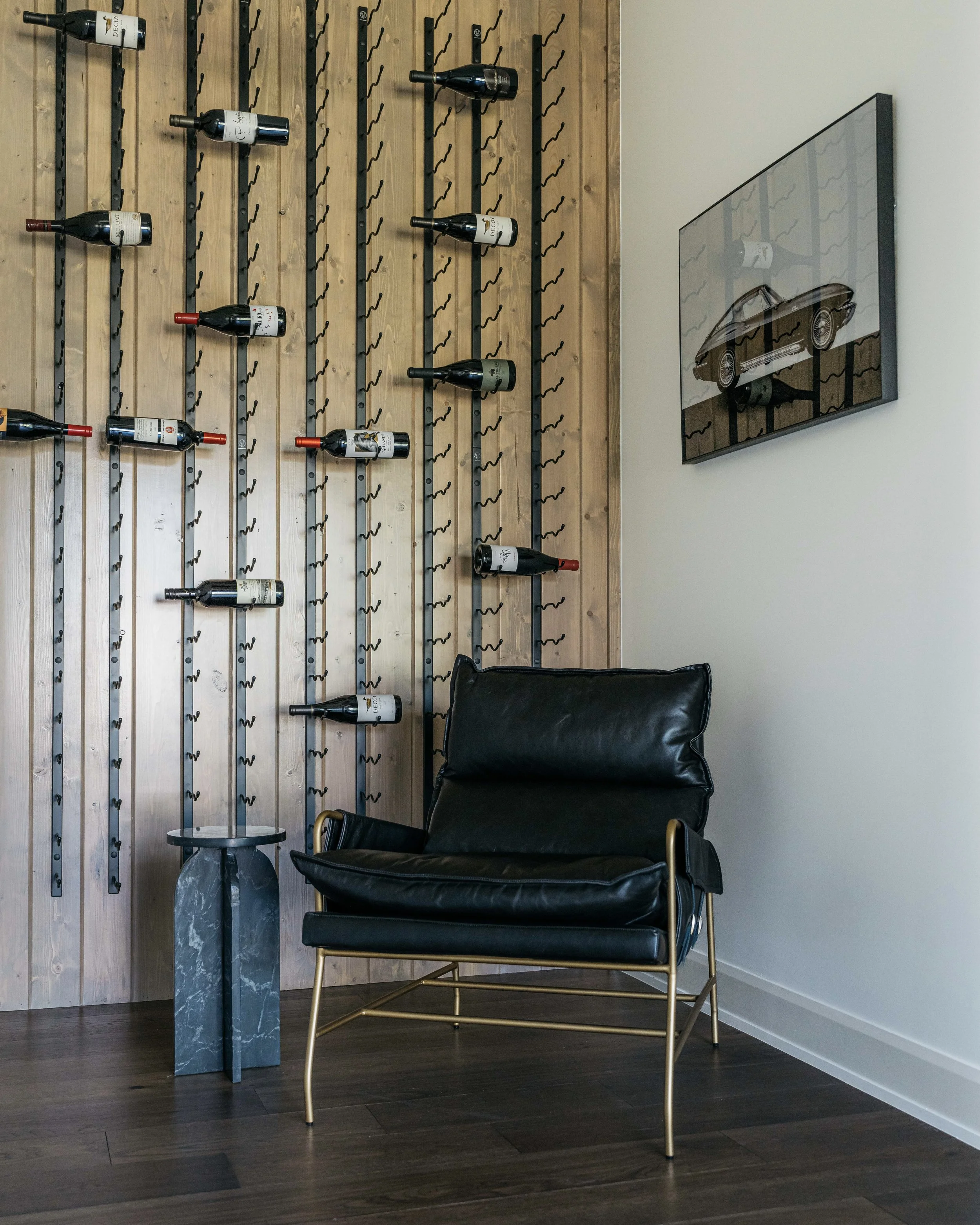 Custom commercial lounge space featuring a built-in wine display, vertical wood slat wall, and refined modern leather seating.