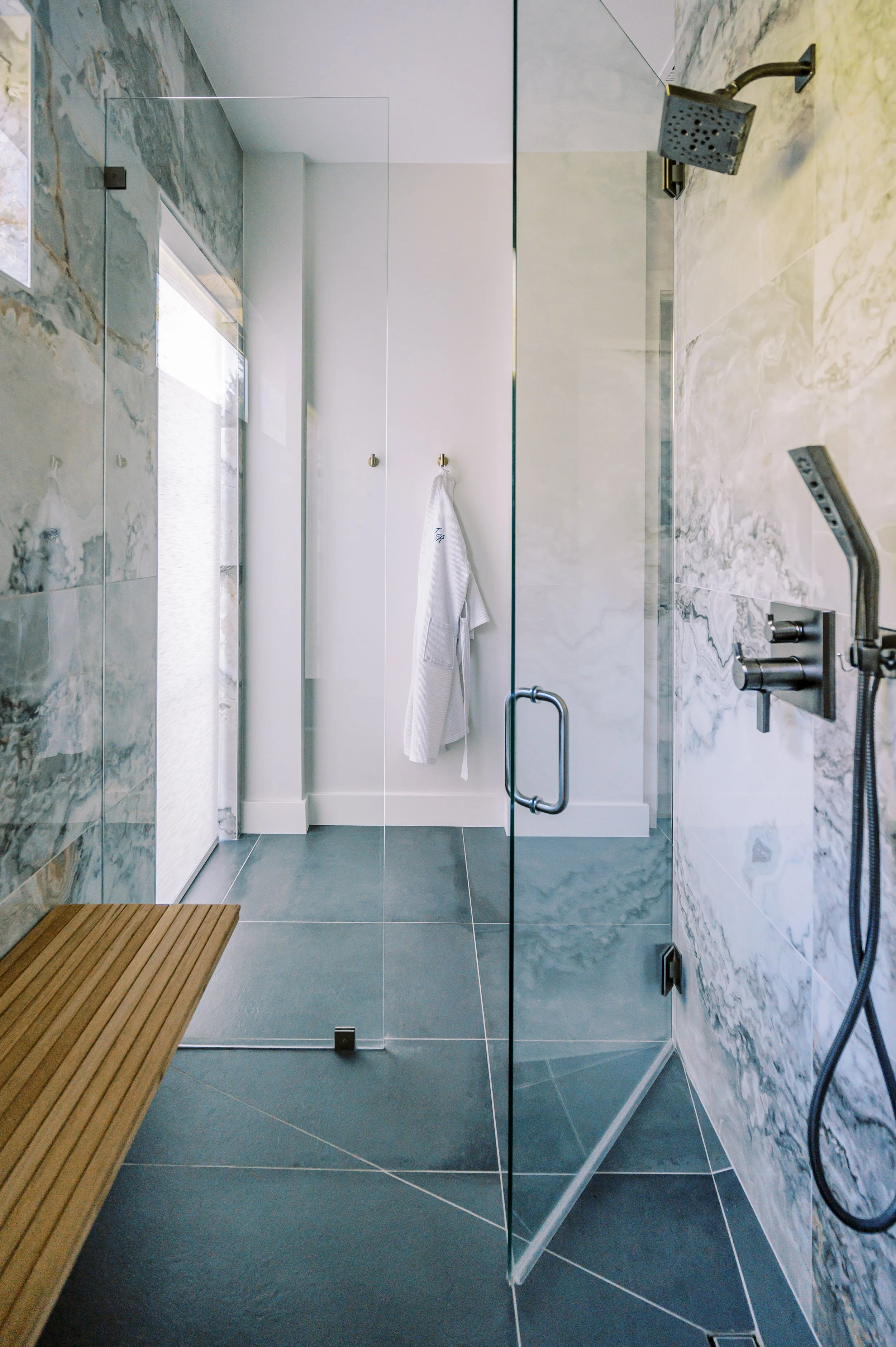 Luxury Cabin Builder IdahoLuxury custom bathroom with glass-enclosed walk-in shower, stone tile walls, and minimalist modern finishes.