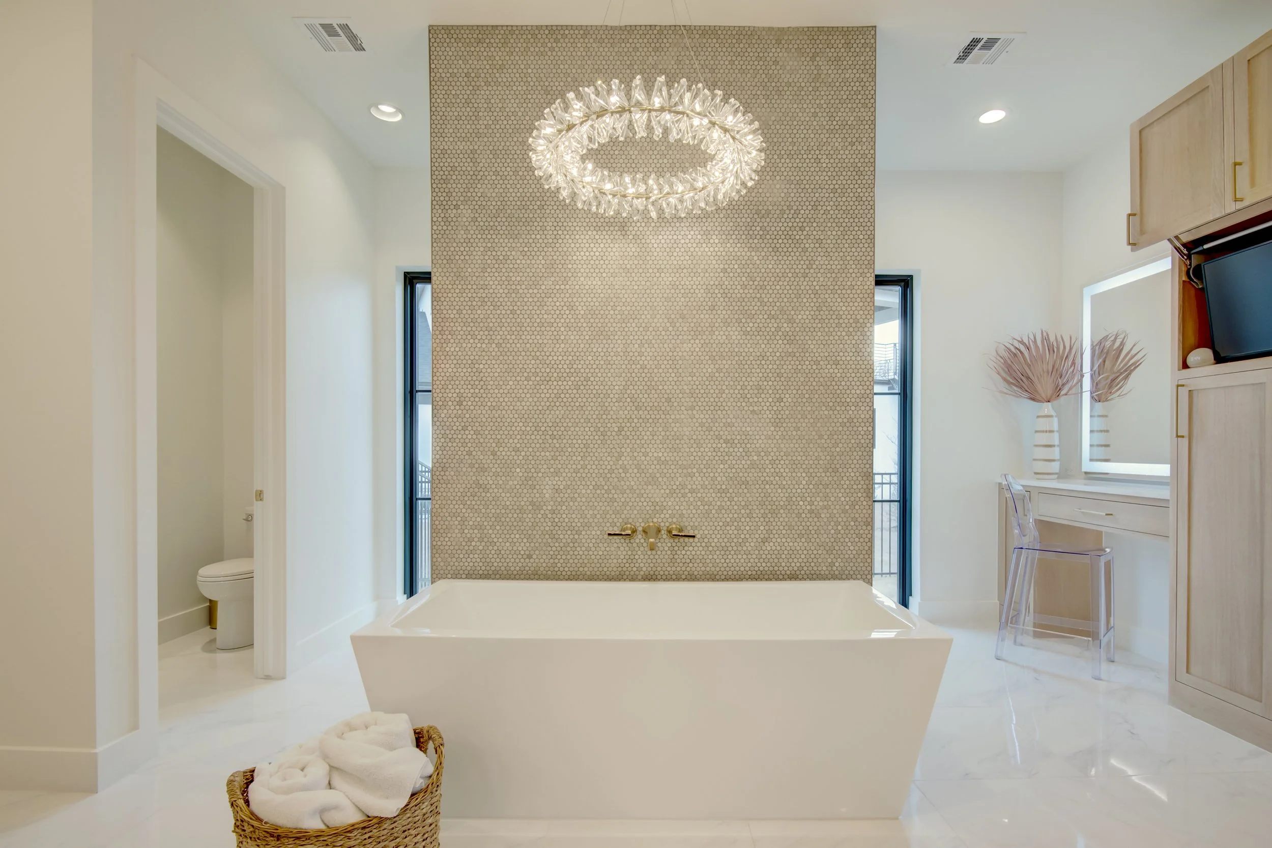 High-end custom bathroom featuring a freestanding soaking tub, statement chandelier, and refined modern finishes.