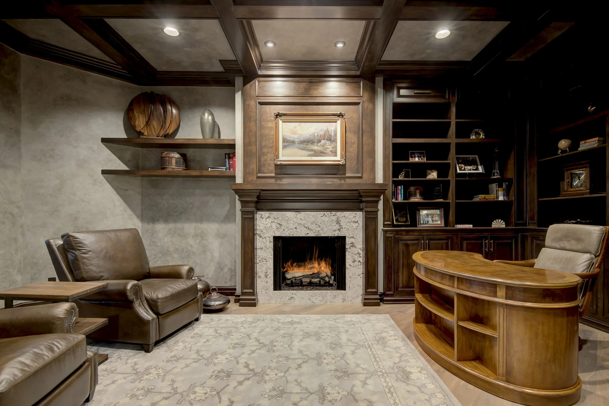 Luxury custom home office featuring rich wood built-ins, a stone fireplace, and classic detailing.
