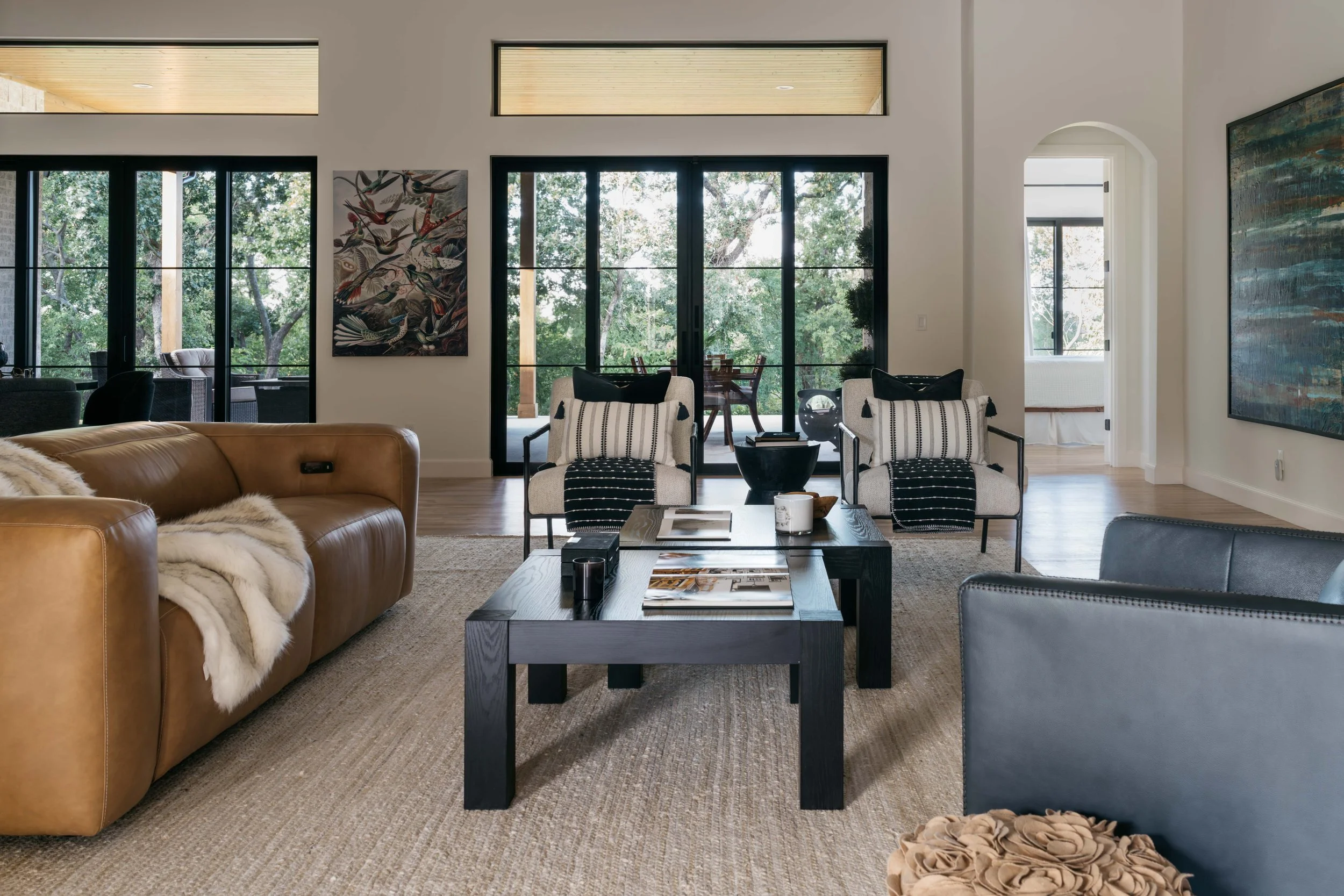 Luxury custom living room with tailored seating, layered textures, and large windows bringing in natural light.