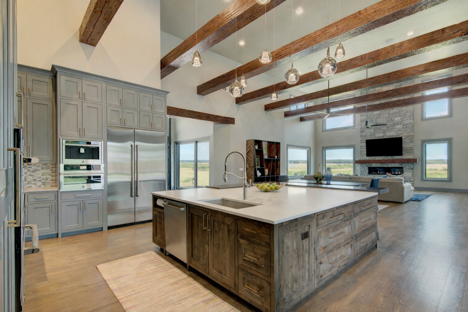 Luxury mountain home kitchen with a custom wood island, exposed ceiling beams, and open-concept great room.