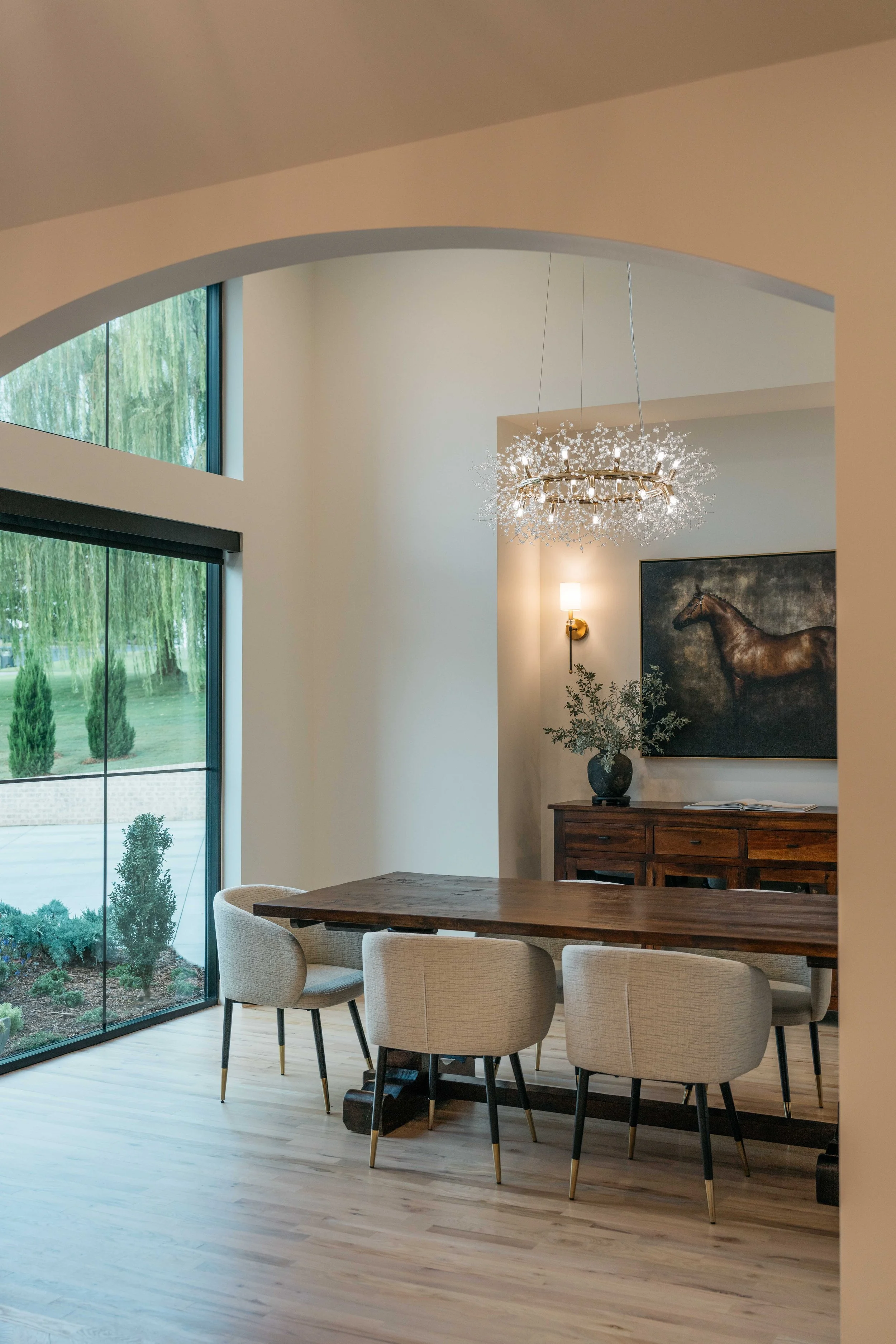 Luxury custom home dining room with vaulted ceiling, statement chandelier, large windows, and refined modern finishes.