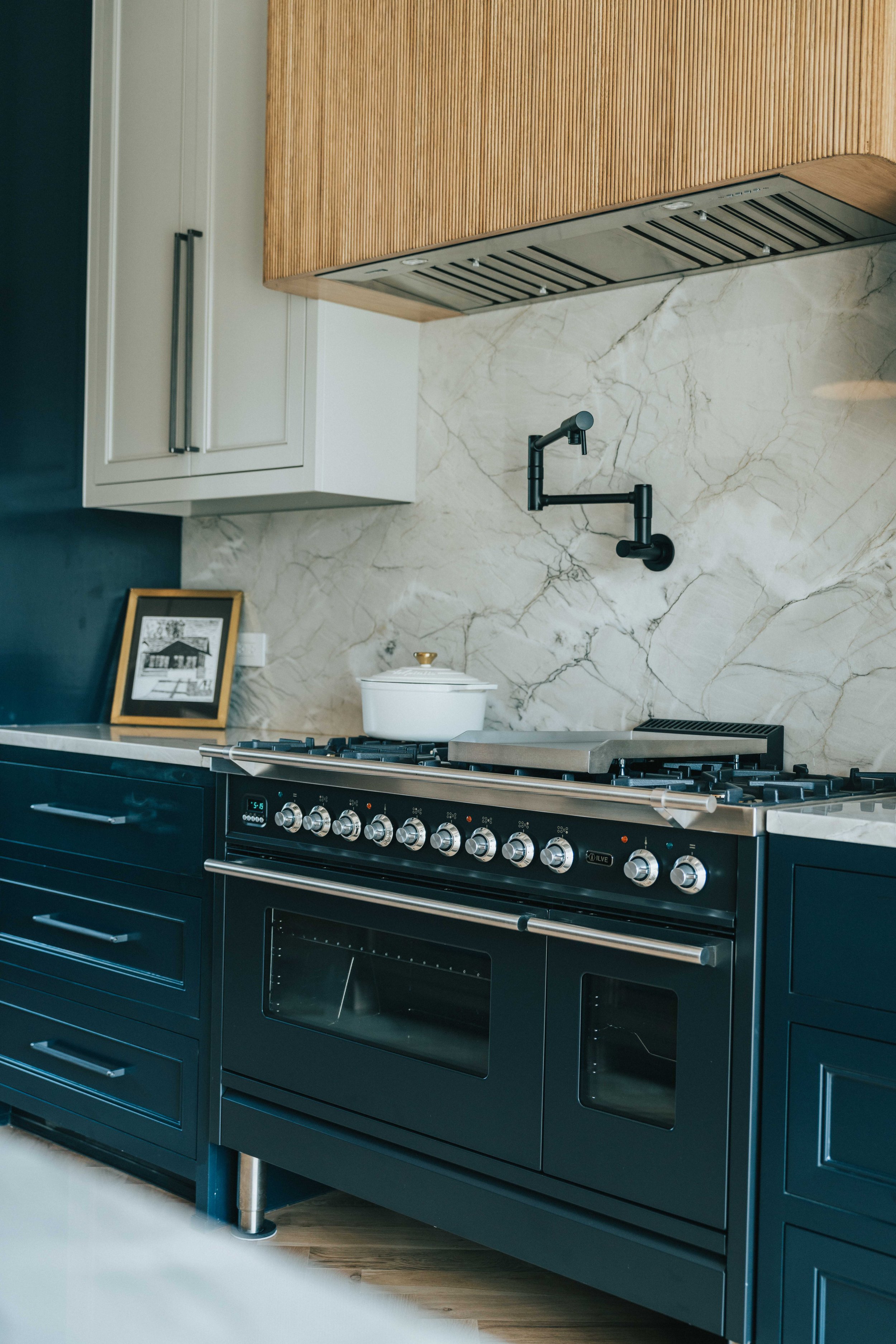 High-end custom kitchen featuring a marble backsplash, professional-grade range, and refined cabinetry.