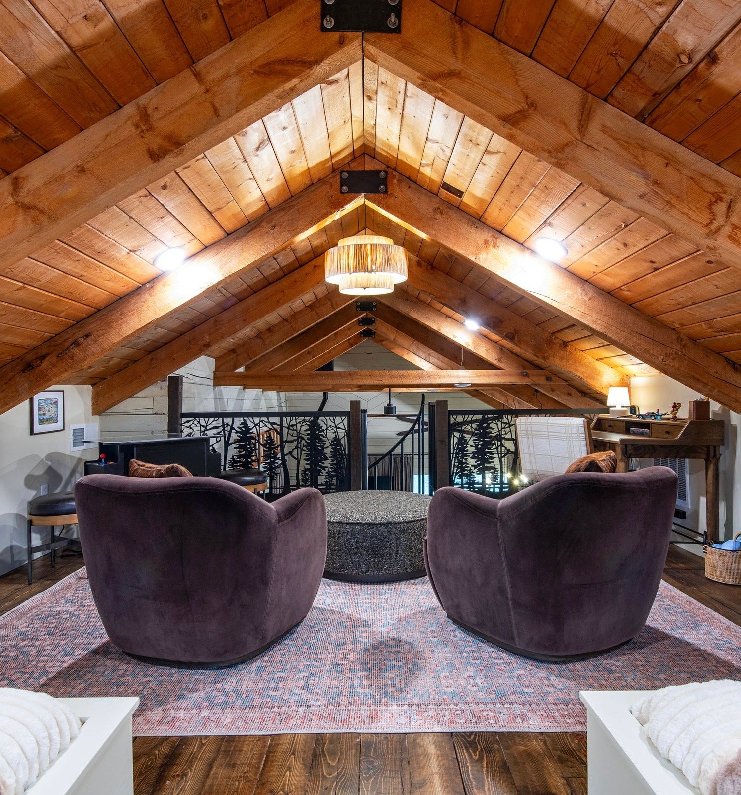 Restored loft interior by Snow Peak Customs featuring exposed timber beams, custom railing, and remodeled mountain home living space.