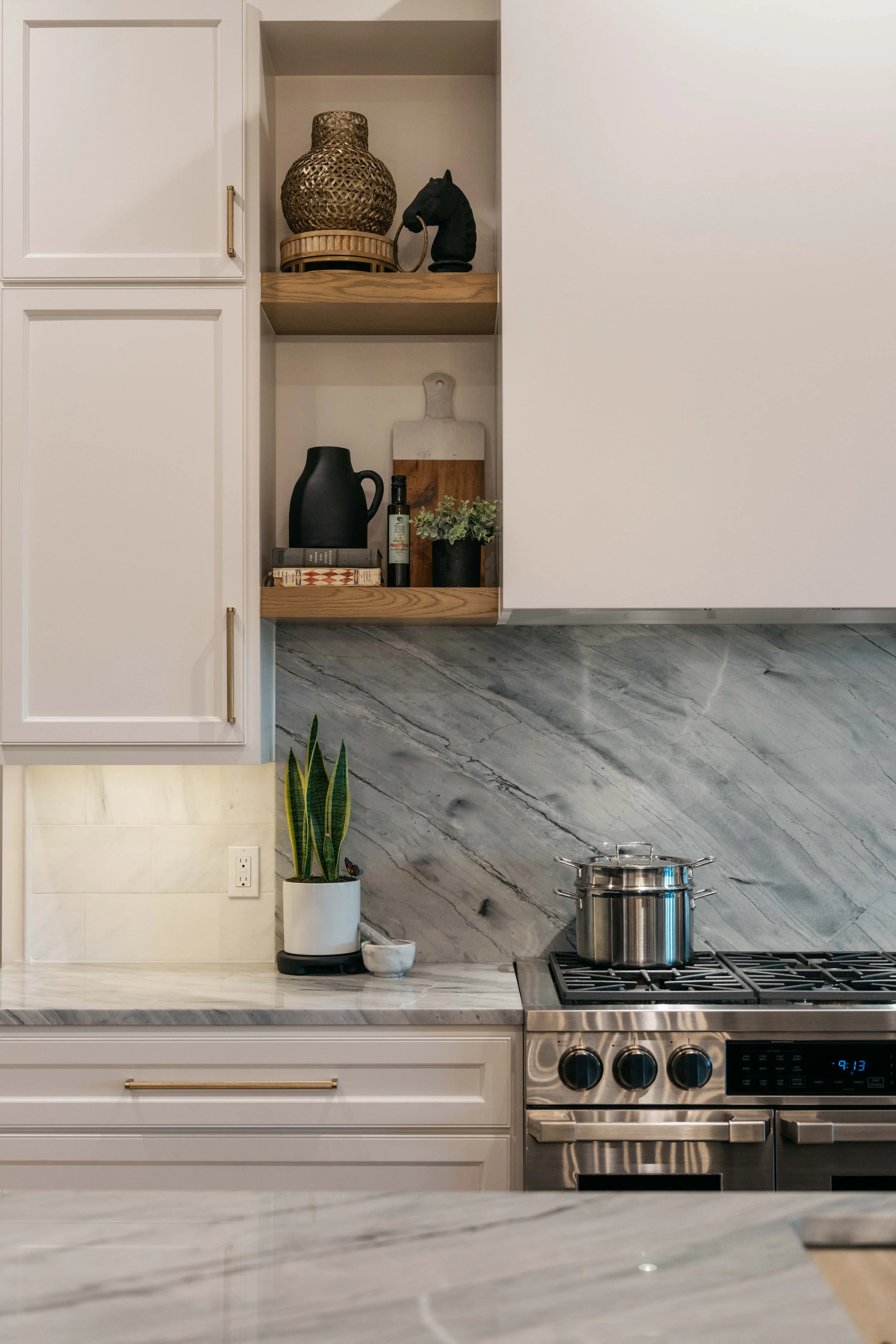 High-end custom kitchen detail with marble backsplash, tailored cabinetry, and professional-grade range.