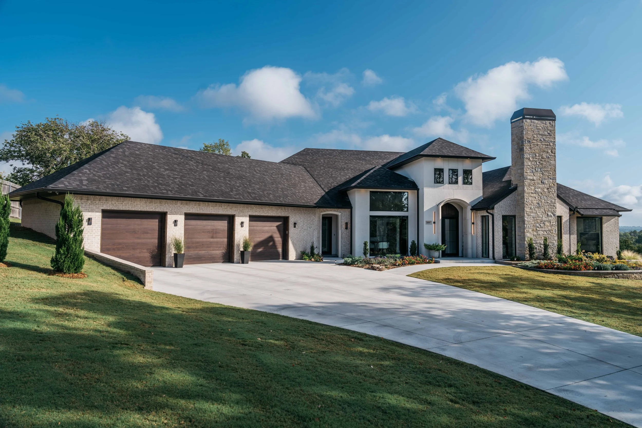 Luxury custom home exterior with stone and brick façade, three-car garage, and modern architectural detailing.