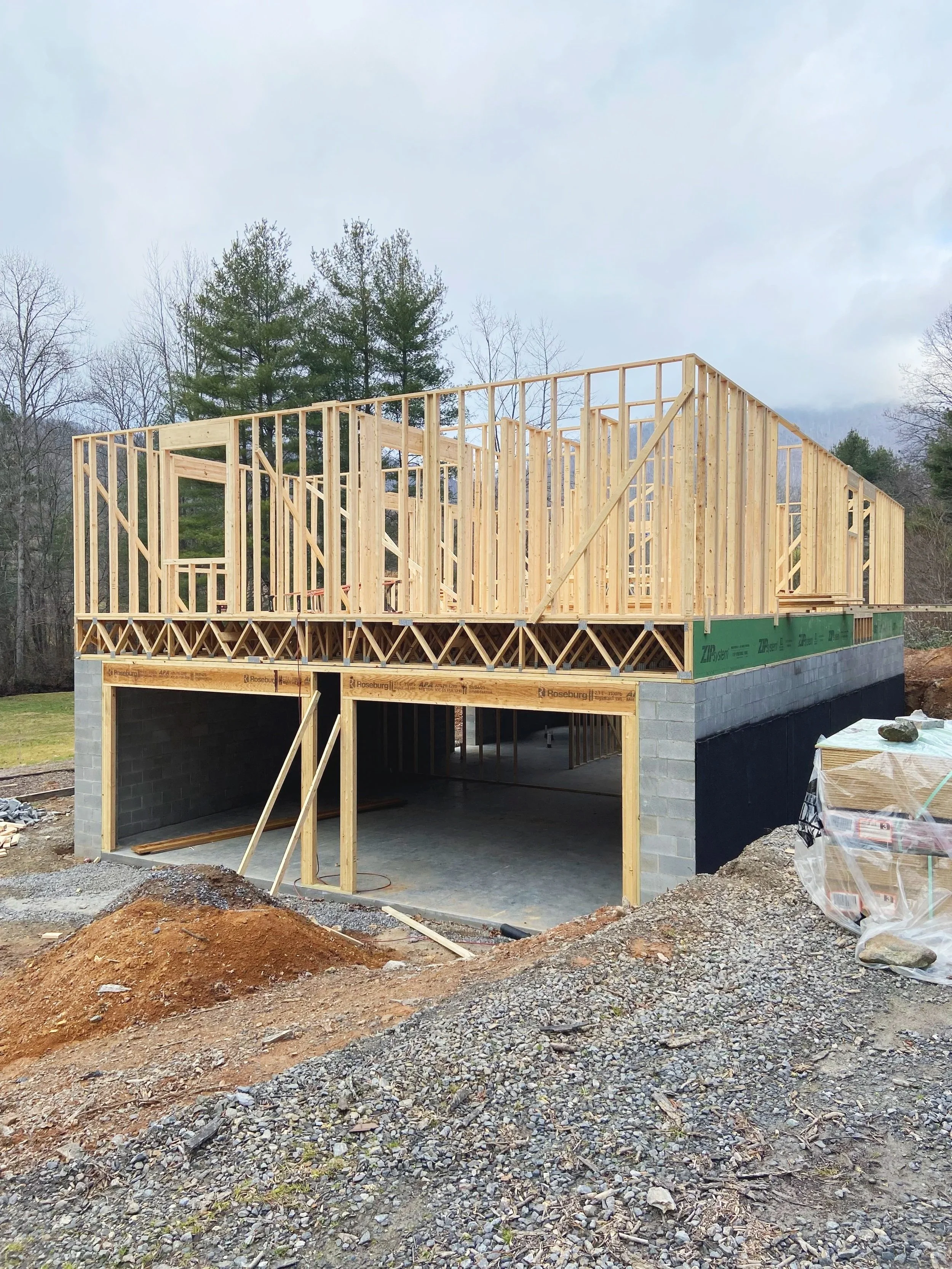 Construction site of a two-story house with a wooden framing structure on top of a concrete block garage.