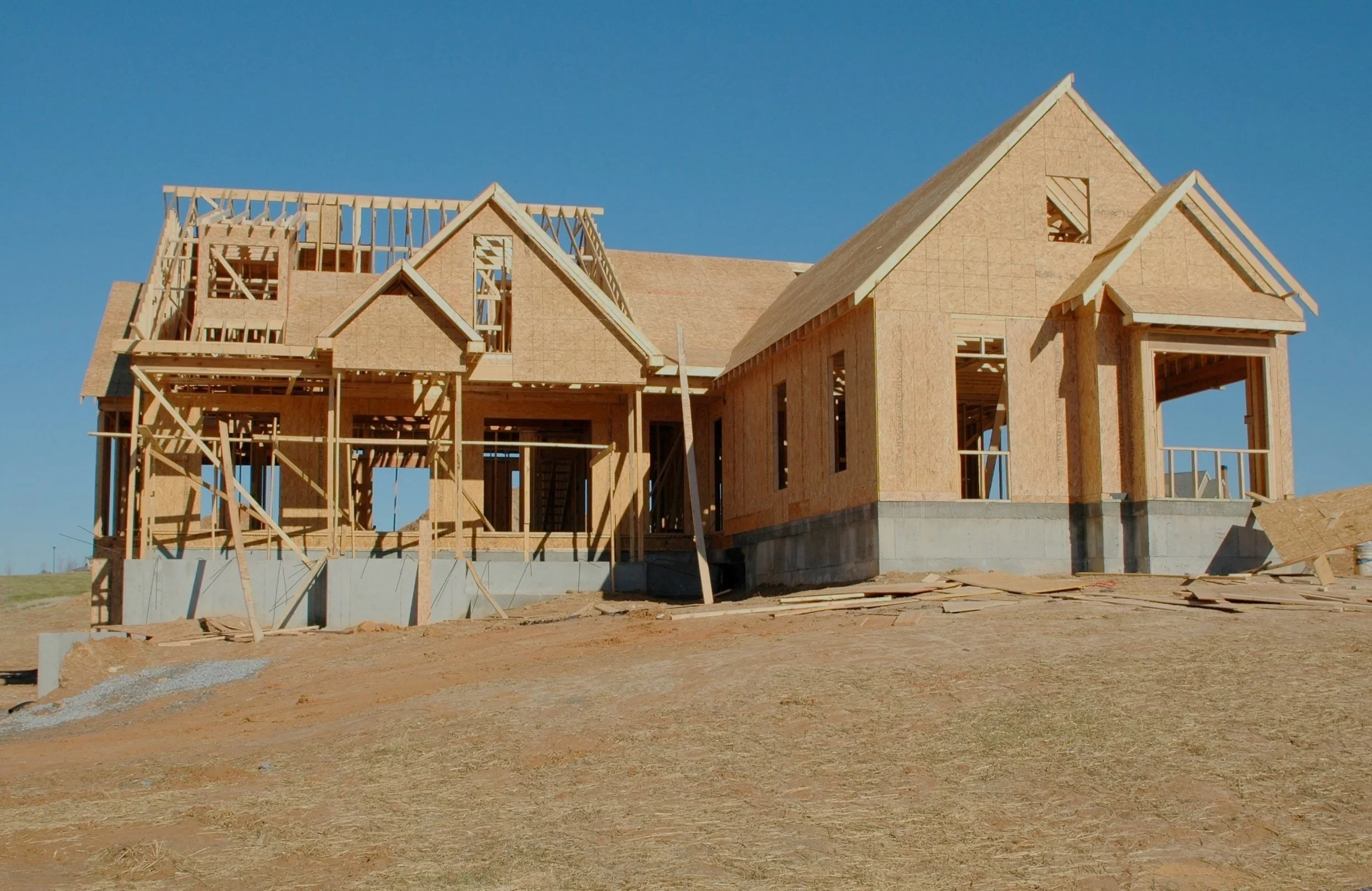 A house under construction with exposed wooden framing and a partially completed roof.