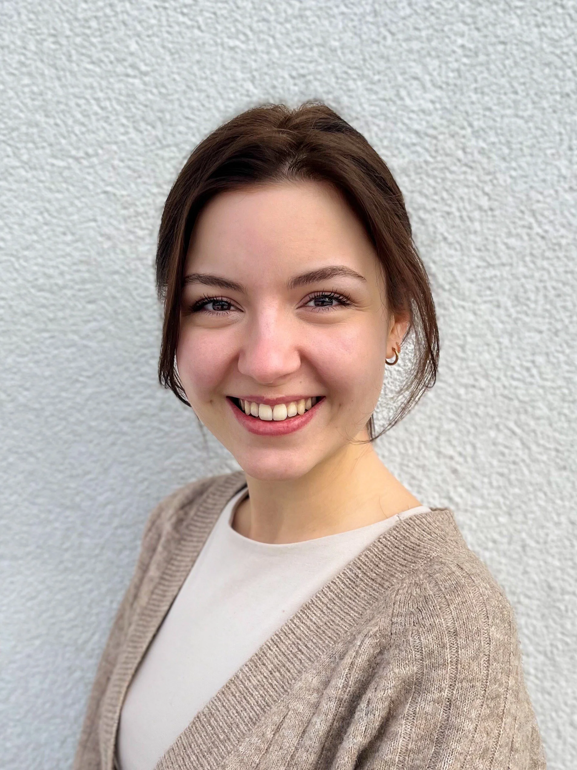 Portrait von der Diätologin Angela Tabery. Eine junge Frau mit braunem, schulterlangem Haar lächelt vor einer weißen Wand.