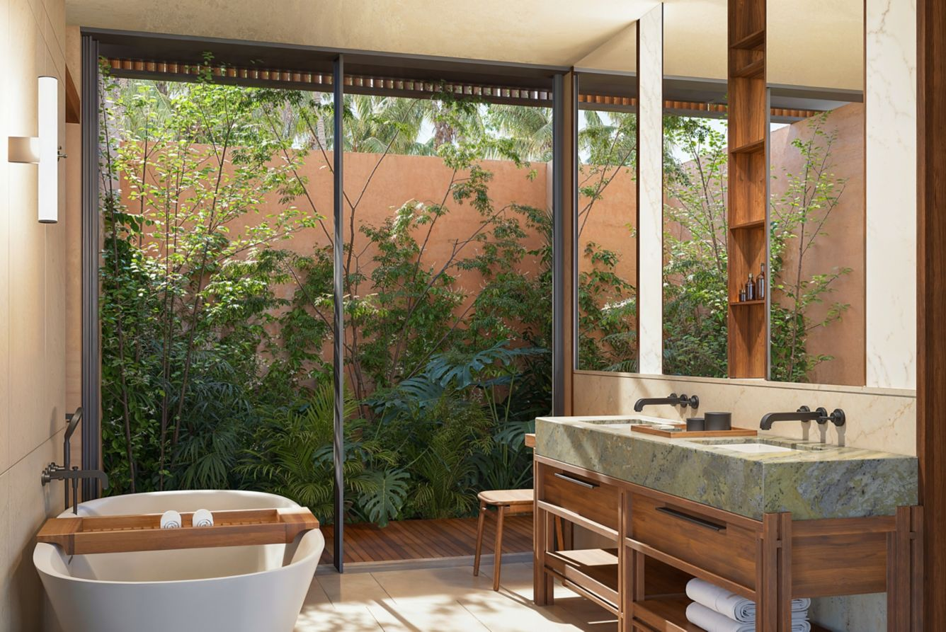Modern bathroom with double sink vanity, wooden cabinetry, large mirror, bathtub, and a large glass window overlooking lush greenery outside.