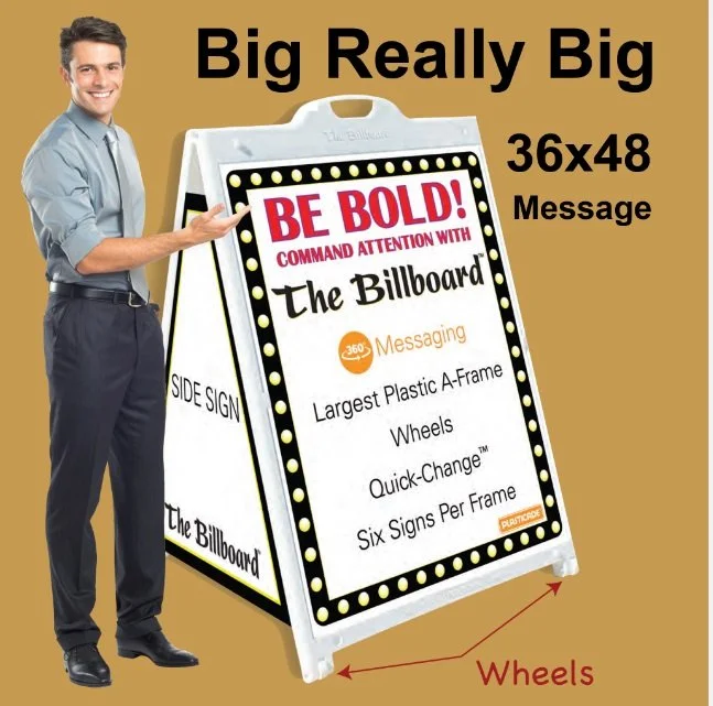 A man standing next to a large, portable advertising signboard promoting a billboard, emphasizing its big size and features like speech wheels and quick-change signs.