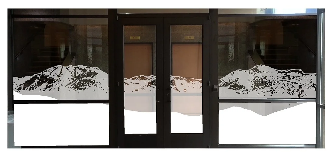 Storefront glass display with mountain landscape decals, consisting of snow-capped peaks, on the lower half of the windows.