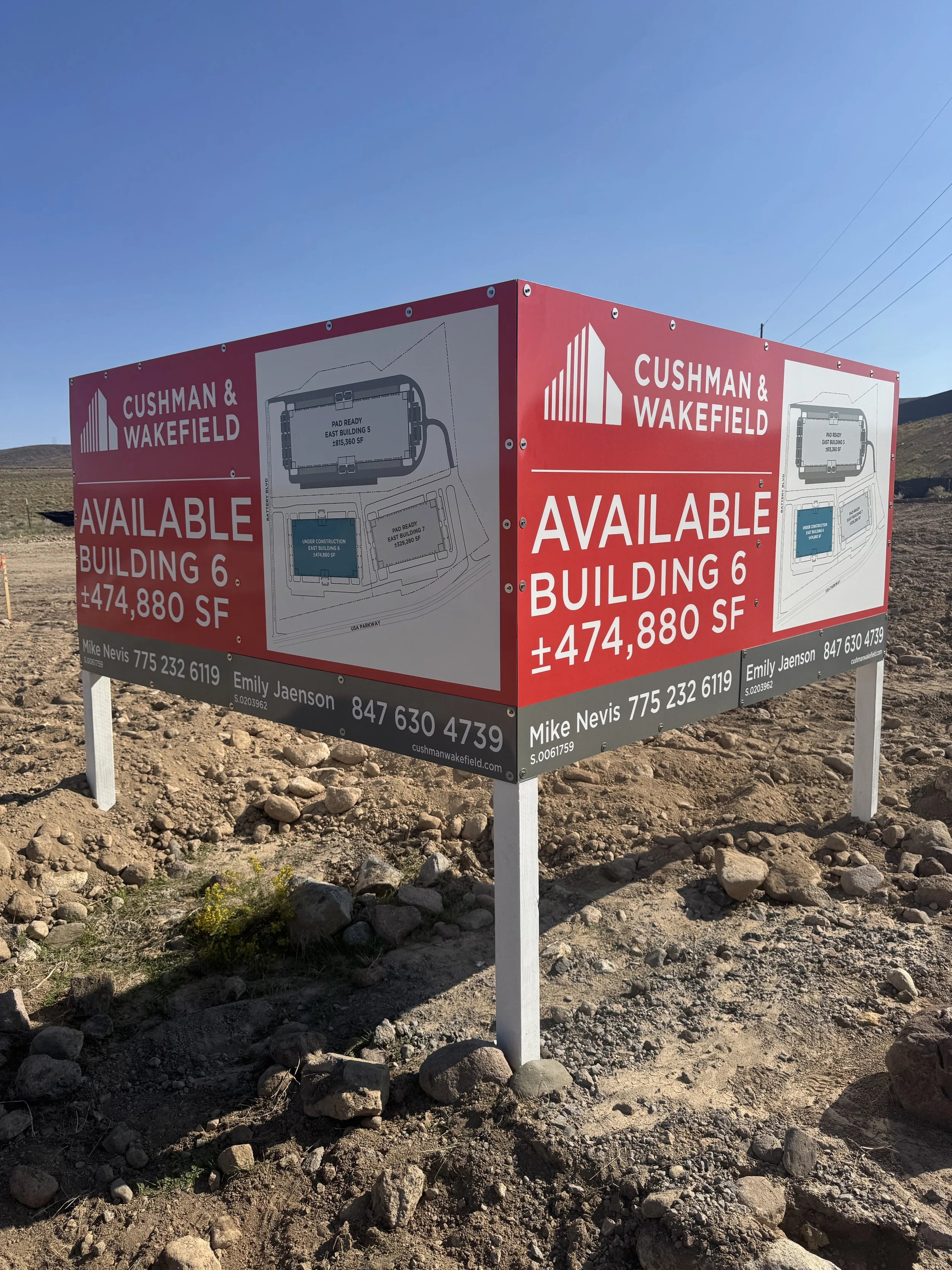 A red and white billboard sign advertising the availability of a new building, Building 6, with approximately 474,880 square feet, located at Cushman & Wakefield, with contact information for Mike Nevis and Emily Jaenson.