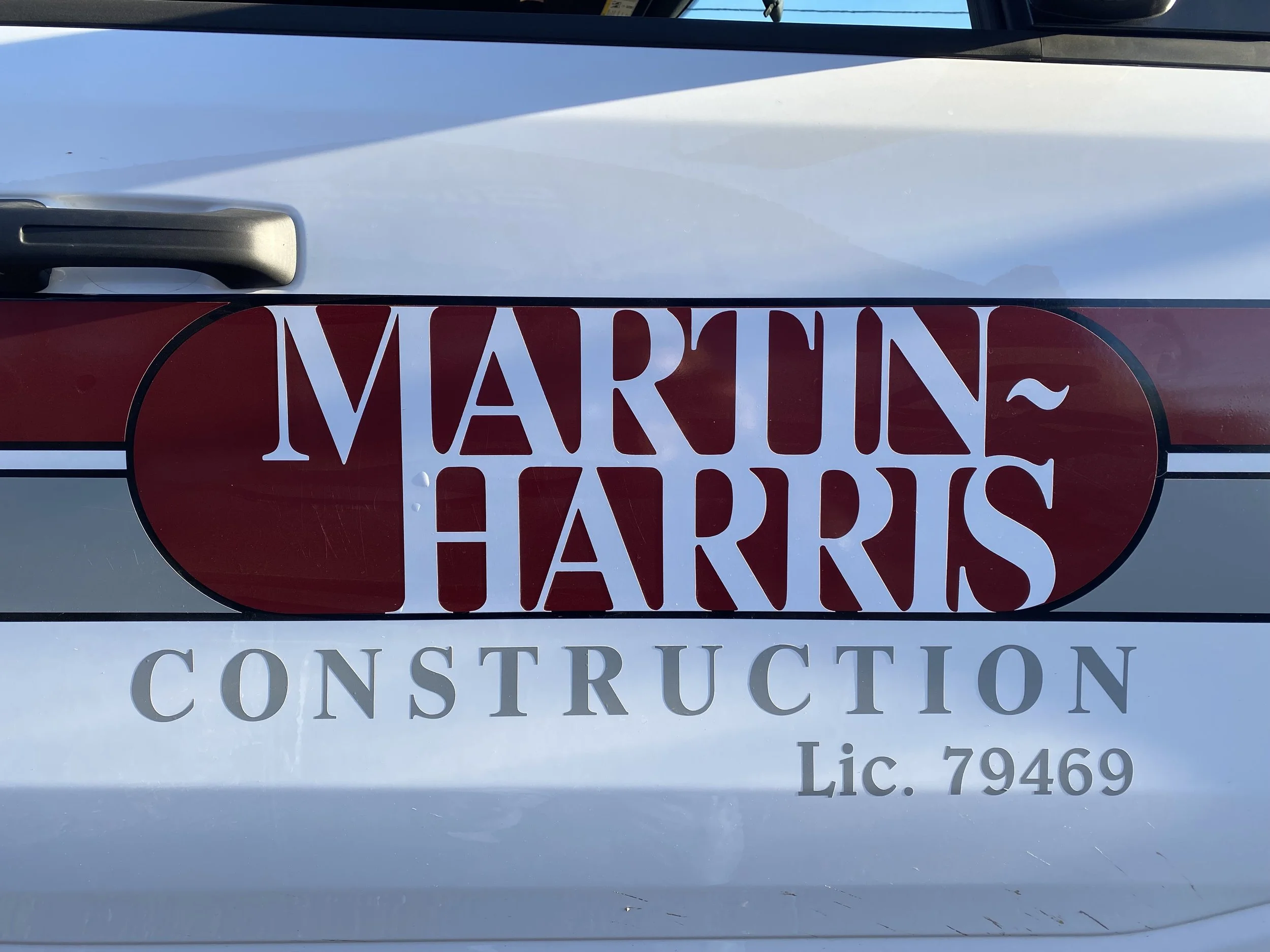 Sticker on a vehicle door displaying 'Martin Harris Construction Lic. 79469' with a red and white oval design.