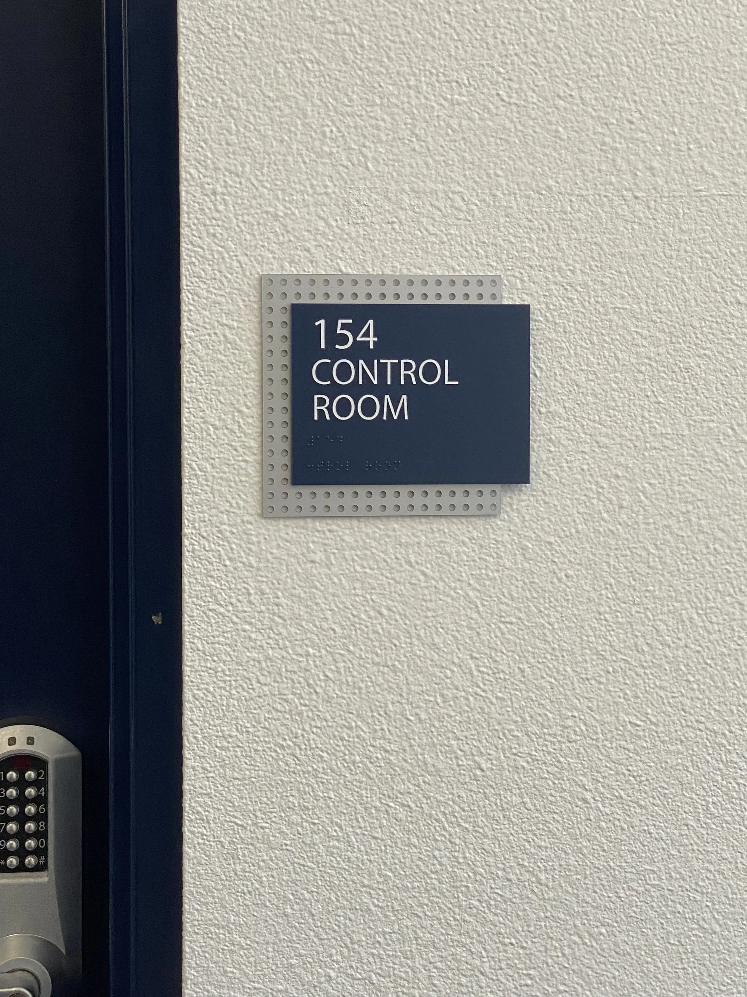 Sign on wall reading '154 Control Room' next to a keypad lock.
