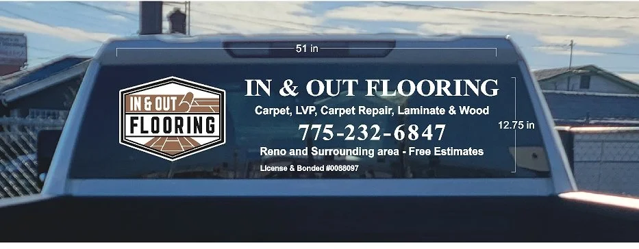 Back window of a truck advertising In & Out Flooring, a flooring business offering carpet, vinyl, carpet repair, laminate, and wood flooring, with contact number 775-232-6847, license number #00880897, located in Reno and surrounding areas. Surroundi