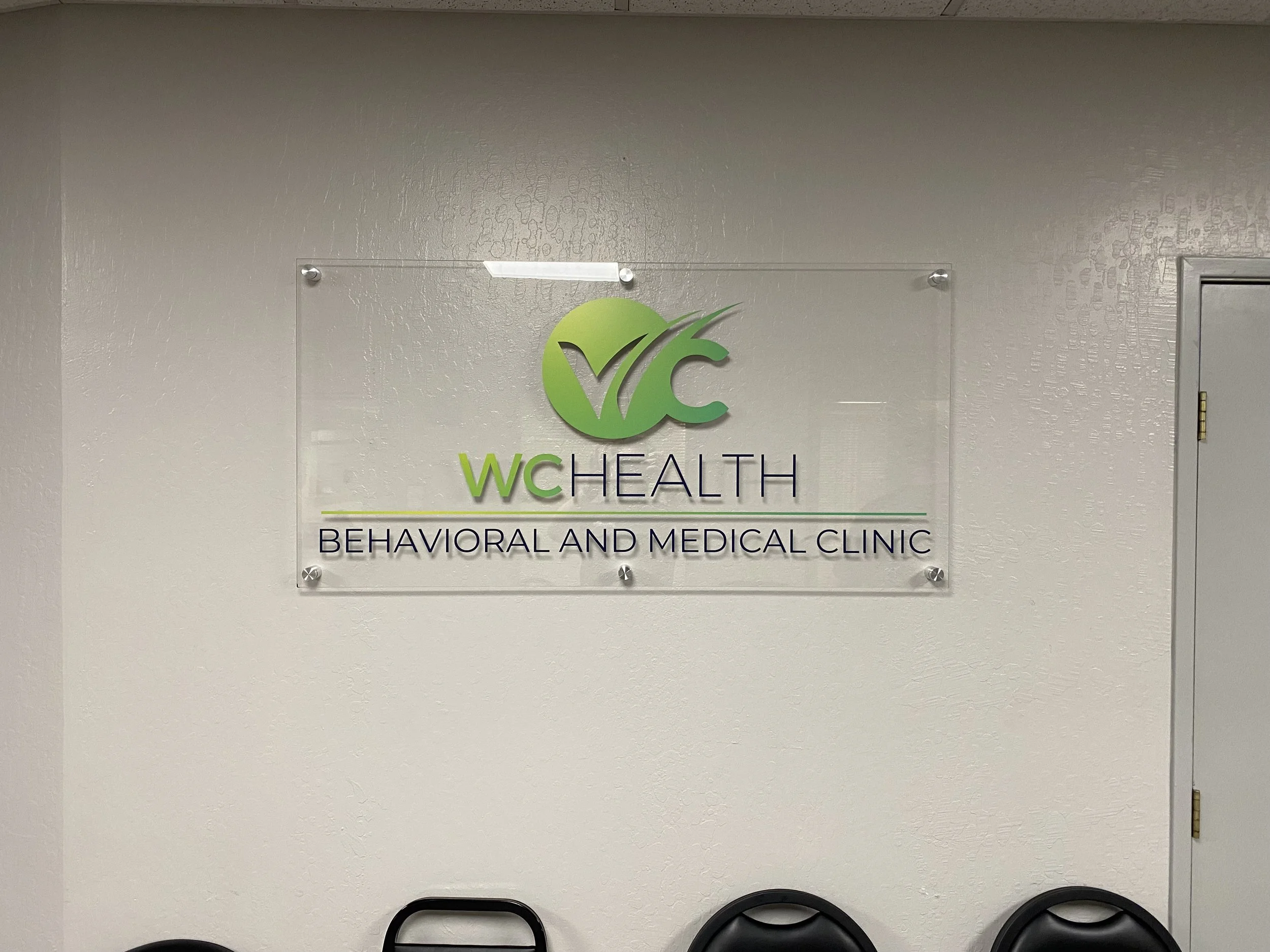 Sign for WC Health Behavioral and Medical Clinic on a light-colored wall