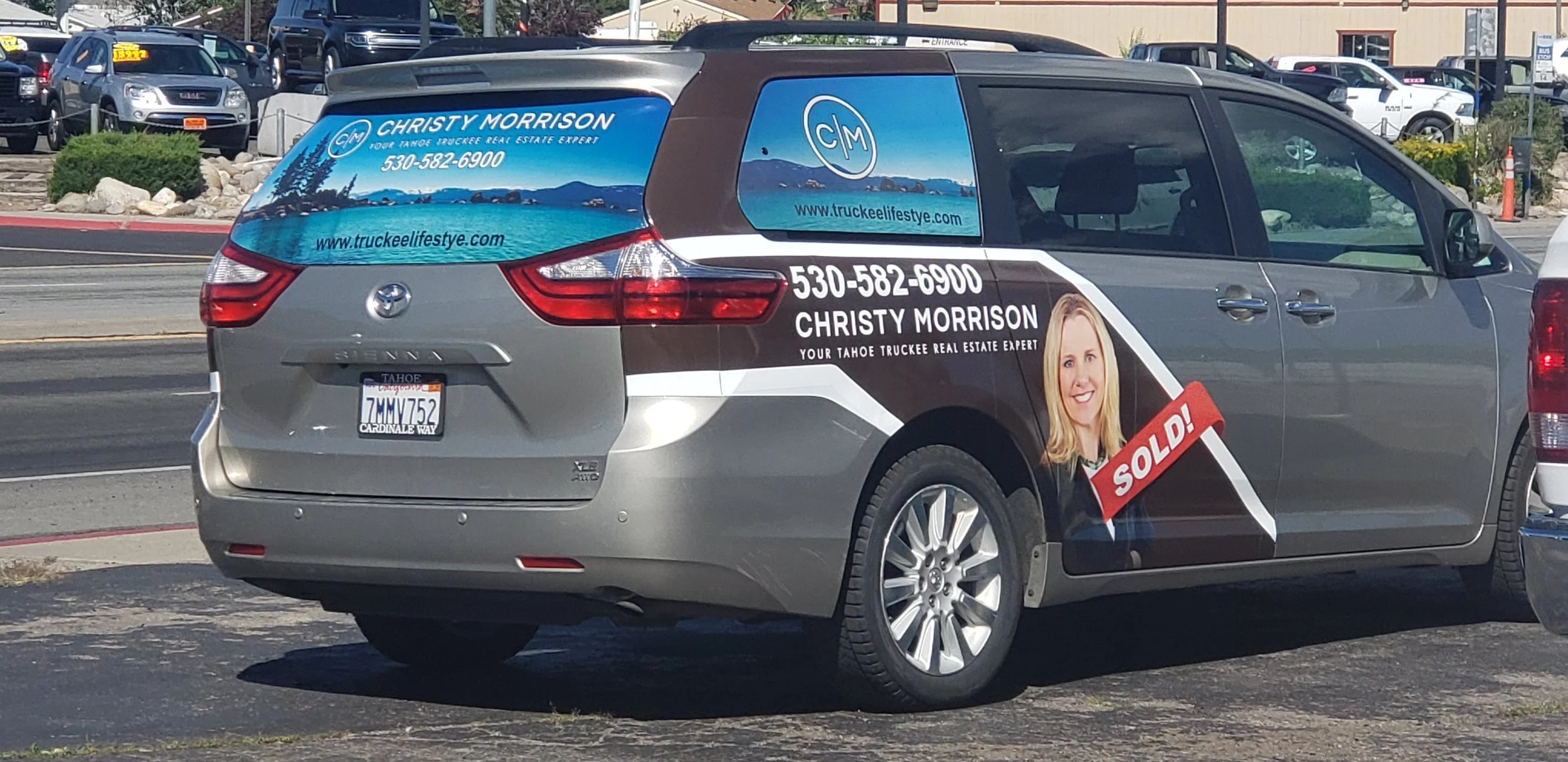 A Toyota Sienna minivan with a real estate advertisement on its side, promoting Christy Morrison, a Tahoe real estate agent, with a large portrait of her, contact information, and a red 'SOLD!' label.