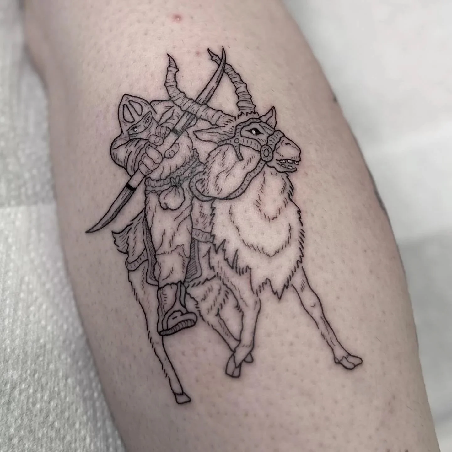 A black outline tattoo of a warrior riding a lion with a horned helmet and holding a spear.