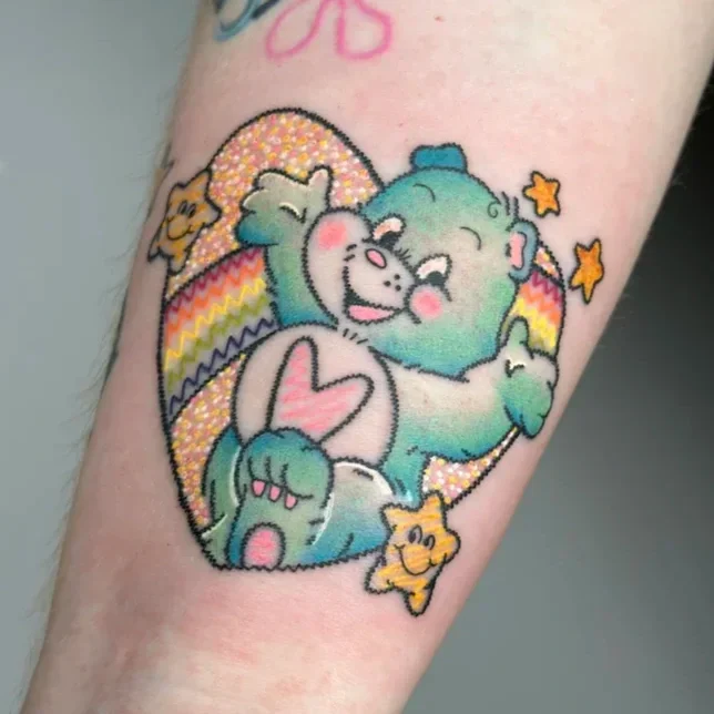Colorful tattoo of a bear, a koala, and a kitten cuddling each other with stars and rainbow background.