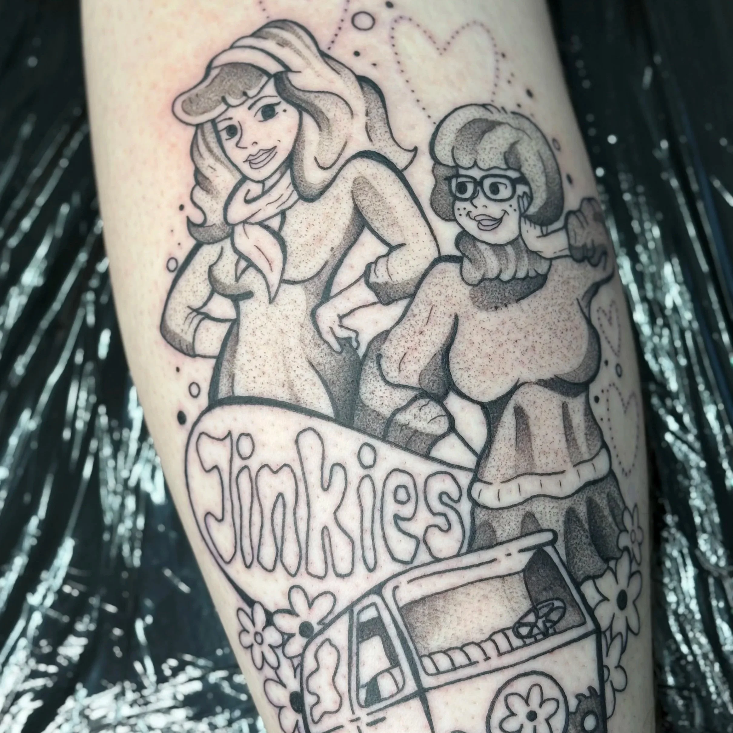 Tattoo of two women in cartoon style with a jinkies sign, flowers, and a van.