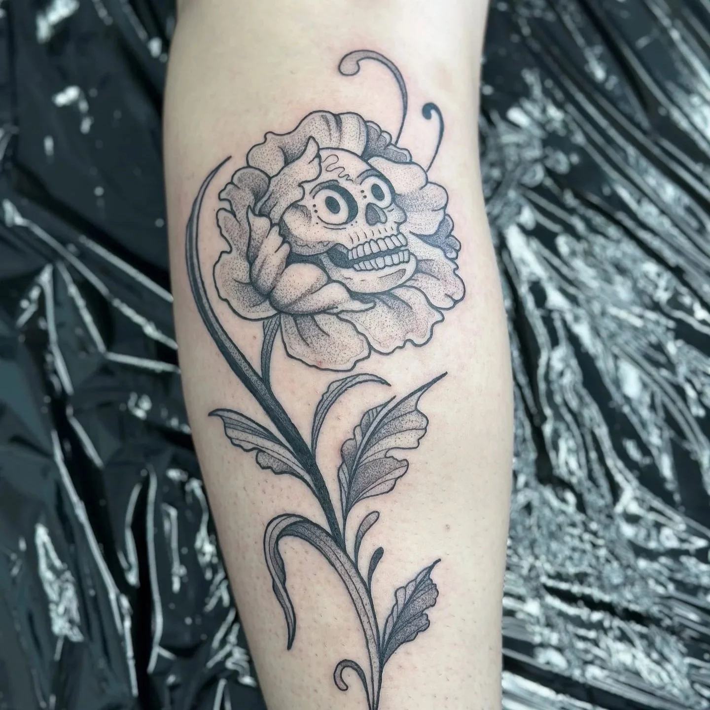 Tattoo of a flower with a skull face inside the flower petals.