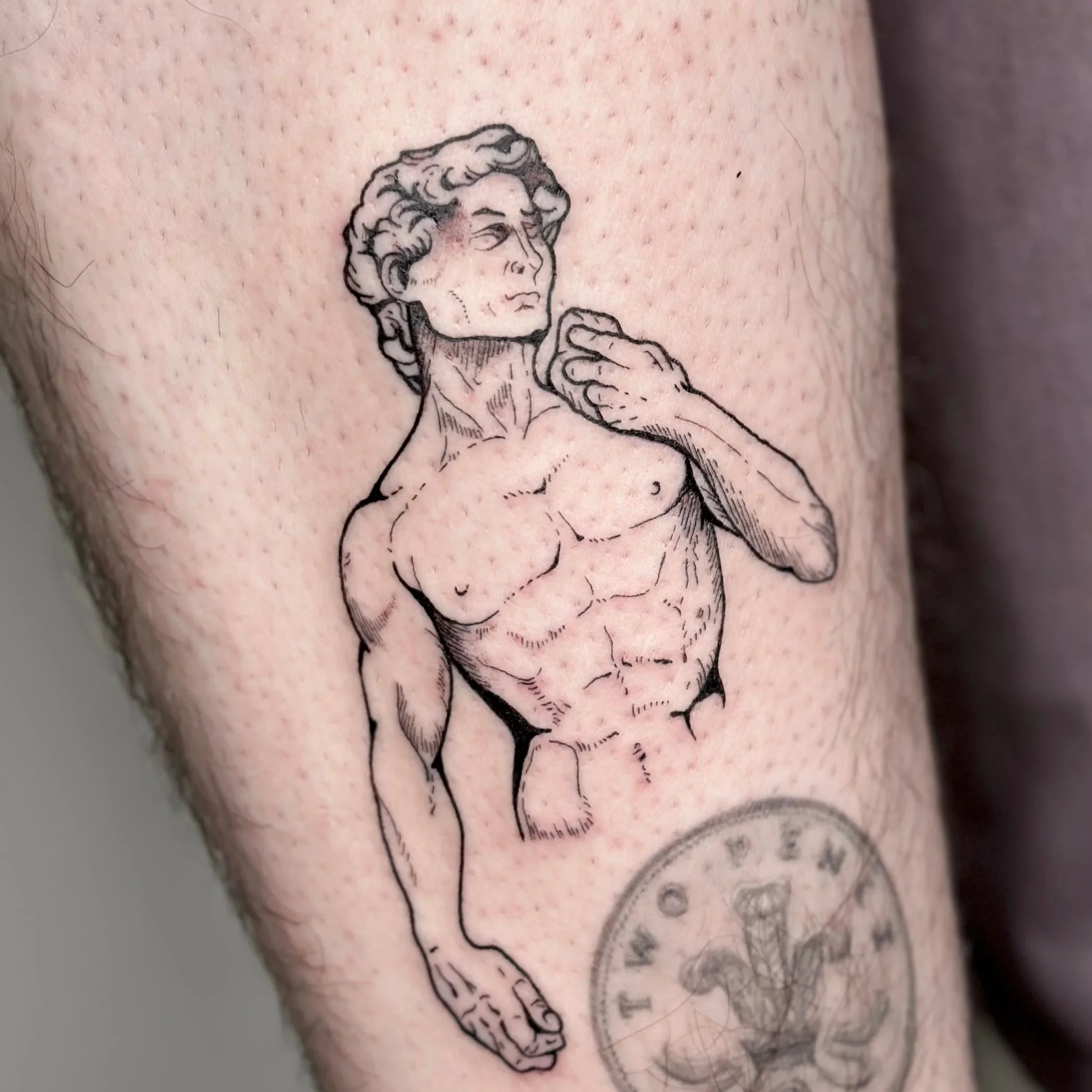 Black line tattoo of a classical male statue with detailed anatomy, looking slightly to the left, with one hand touching his neck, on a person's arm.