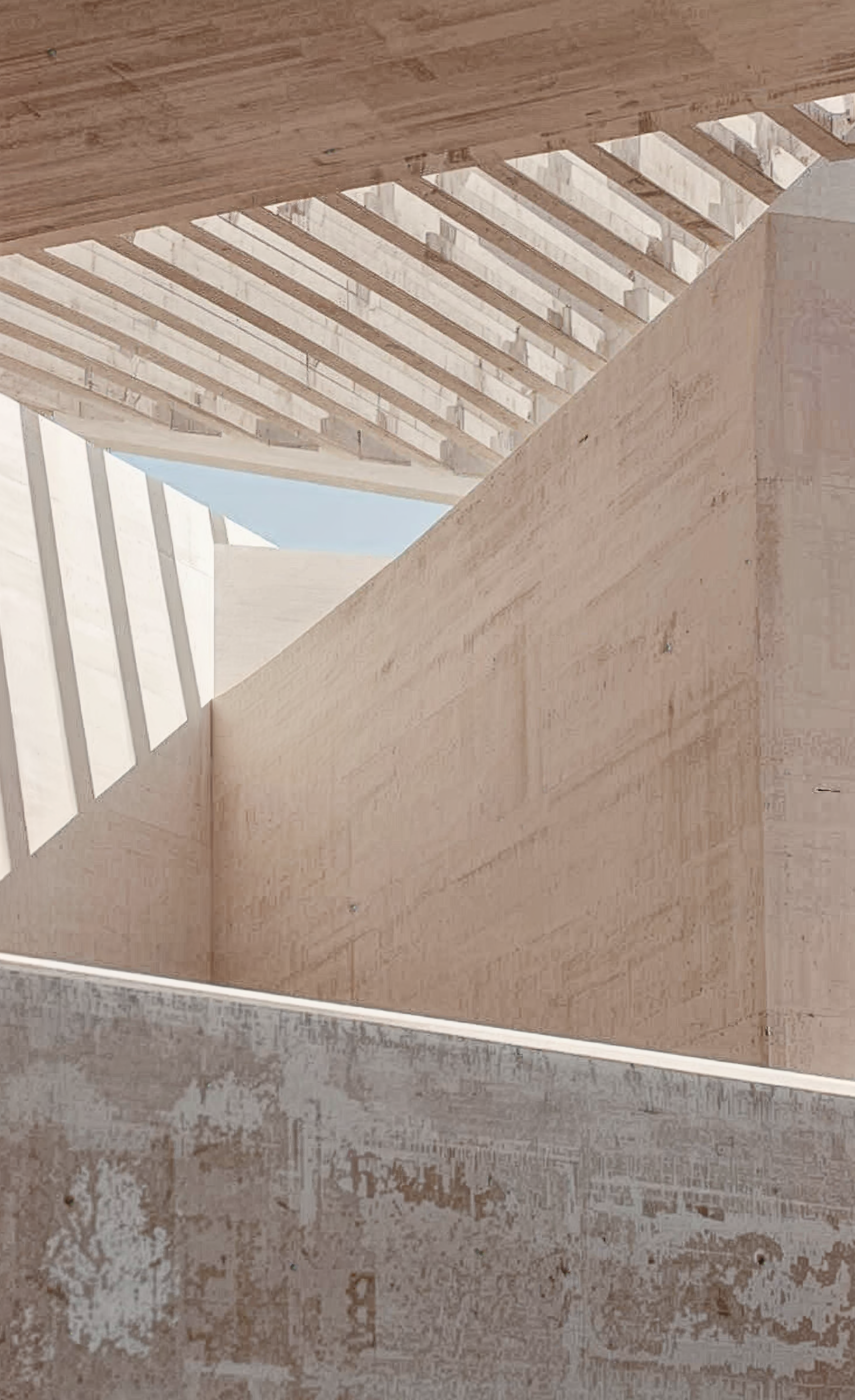 View of modern architectural design with beige walls, wooden ceiling structure, and sunlight casting shadows through slats.