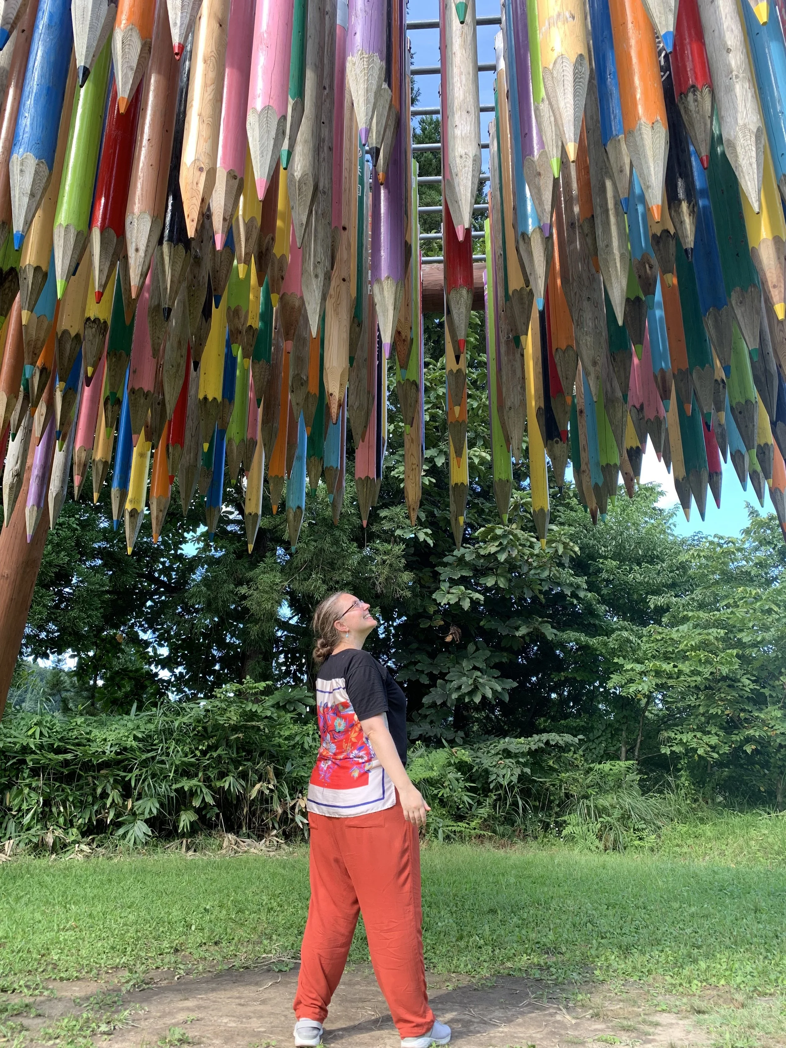 A woman stands under a sculpture of giant colored pencils suspended in air in Niigata, Japan.