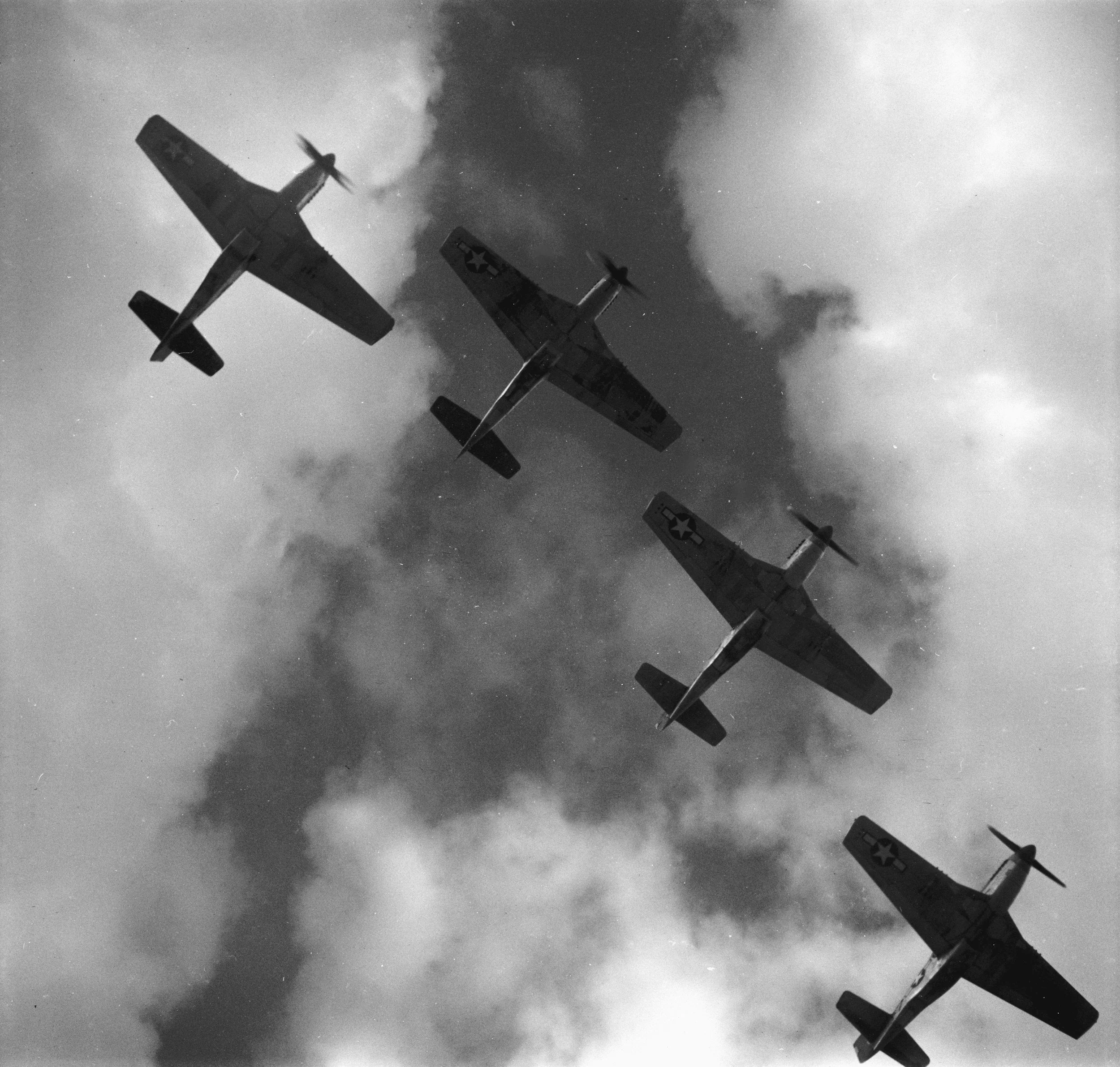 Four vintage military fighter planes flying in formation against a cloudy sky.