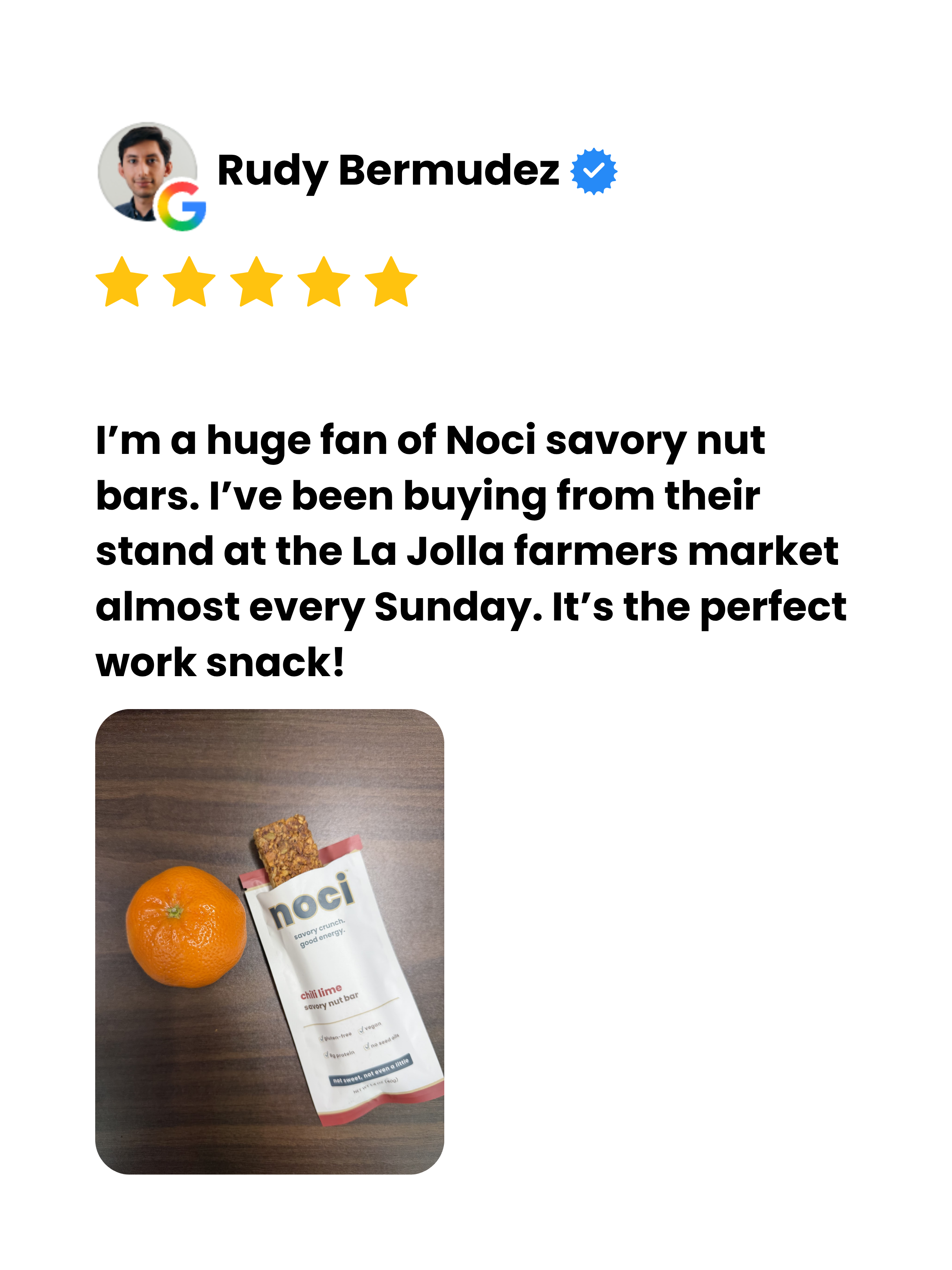 review showing an orange, a packet of noci savory nut bar, and a wooden surface.