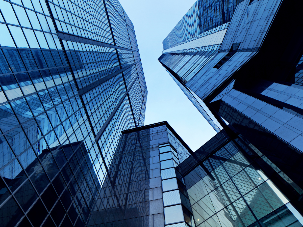 Looking up at tall modern glass skyscrapers reflecting the sky.
