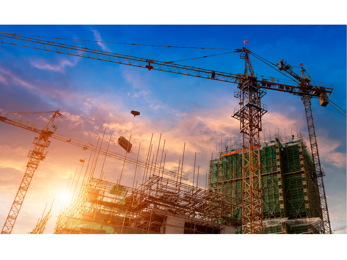 Construction site with cranes and scaffolding during sunset.